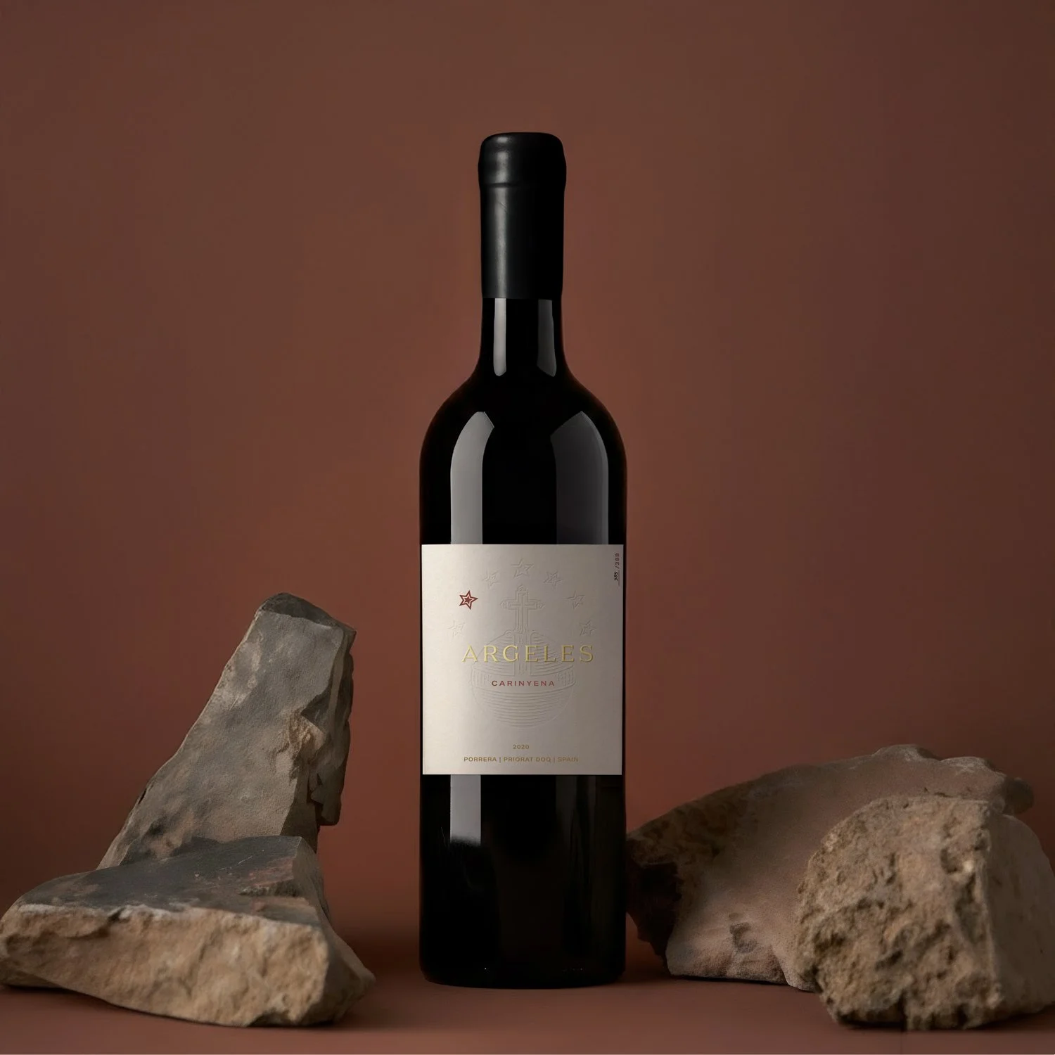 A bottle of Argeles Carinyena red wine placed between two rocks on a brown background.