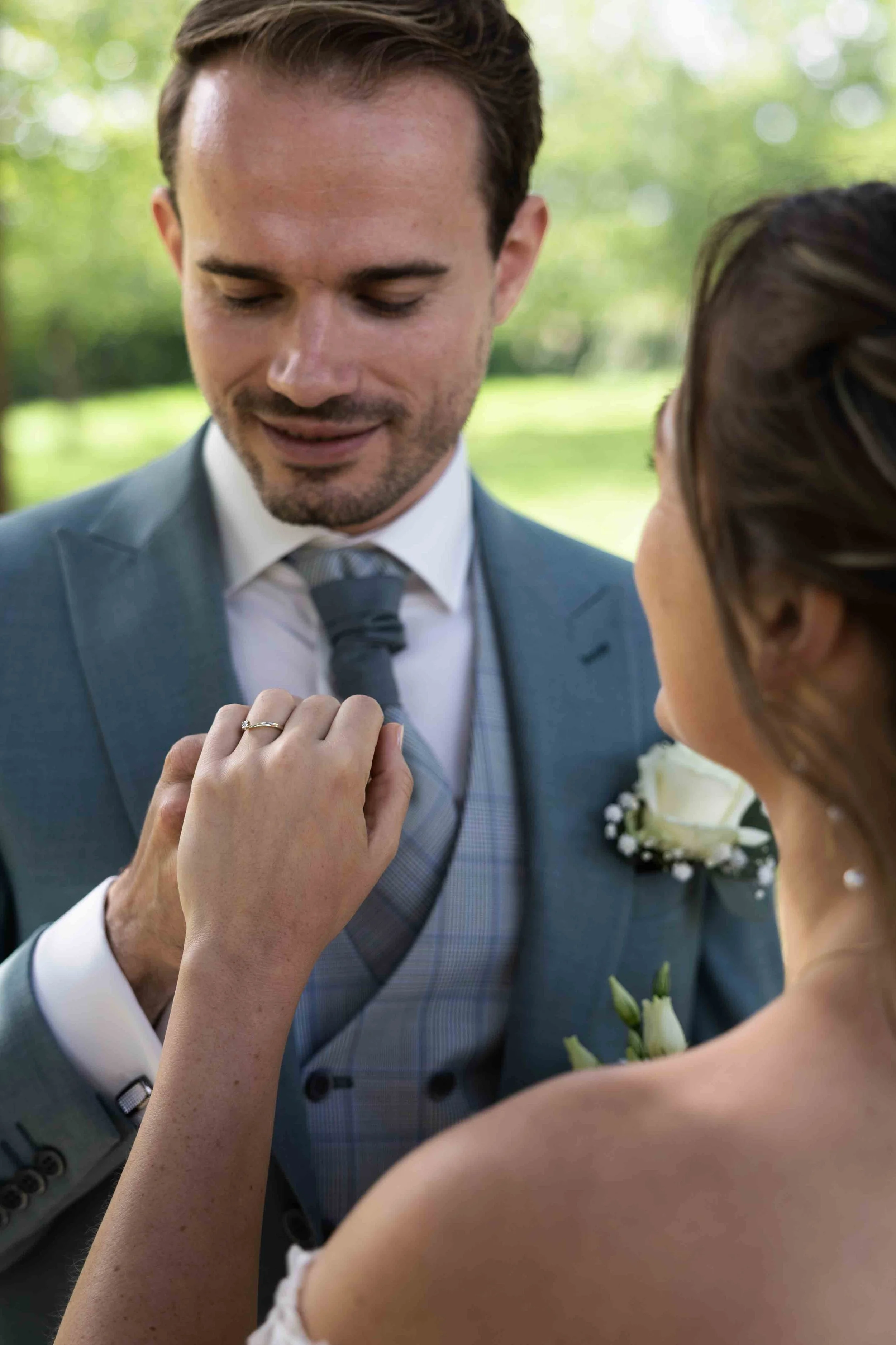 bruidegom heeft de hand van de bruid vast en kijkt naar de verlovingsring