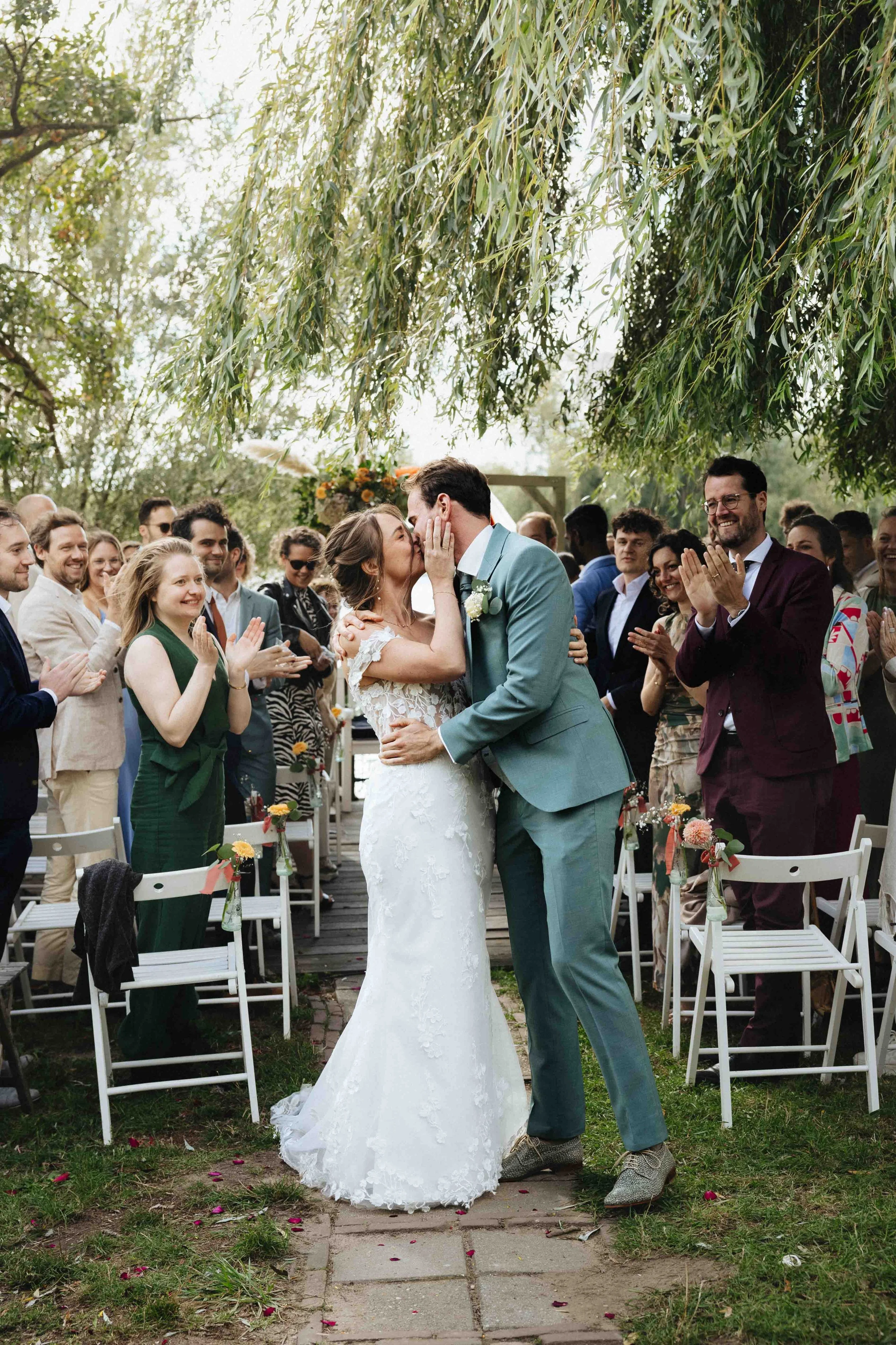 gelukkig bruidspaar in de zomer in nijmegen met gasten op de achtergrond