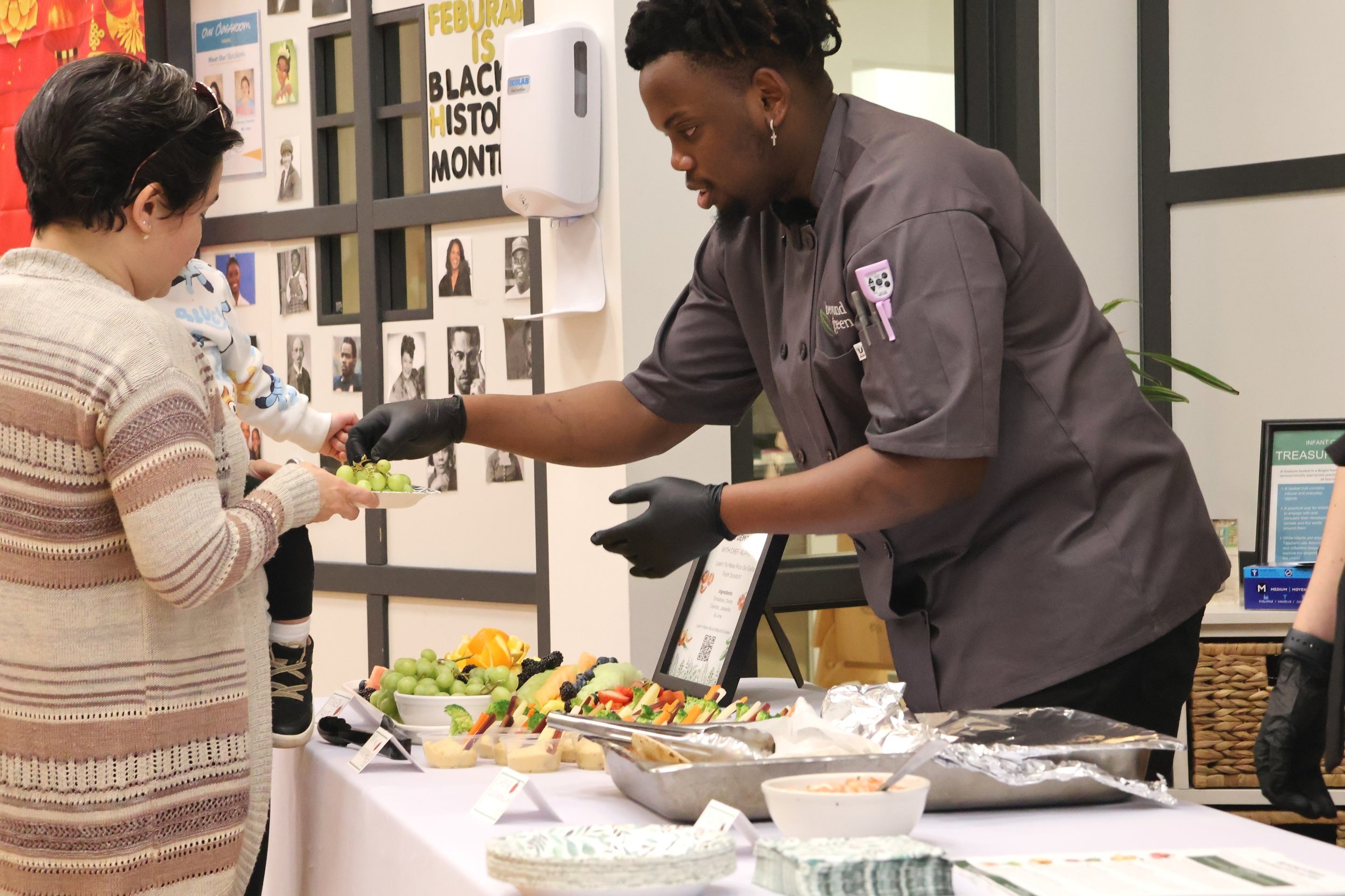 Chef serving fruit to a parent at a preschool event