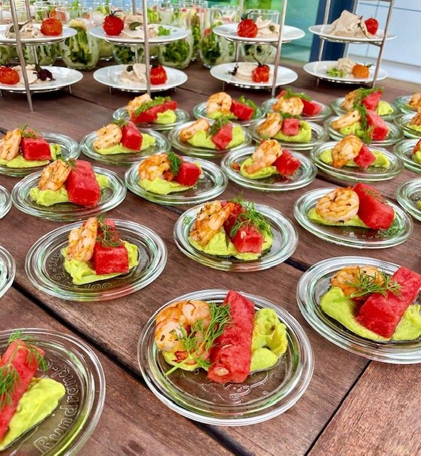 Vorspeisen auf Tellern mit Garnelen, Wassermelone und Avocadocreme.