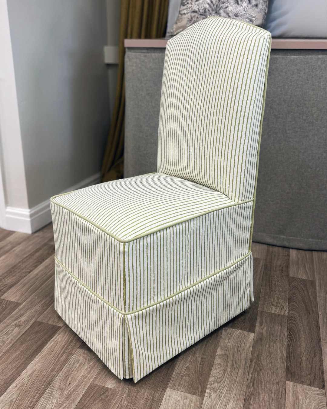A upholstered dressing chair with green vertical stripes by The Pure Edit in the Aconite Interiors workshop