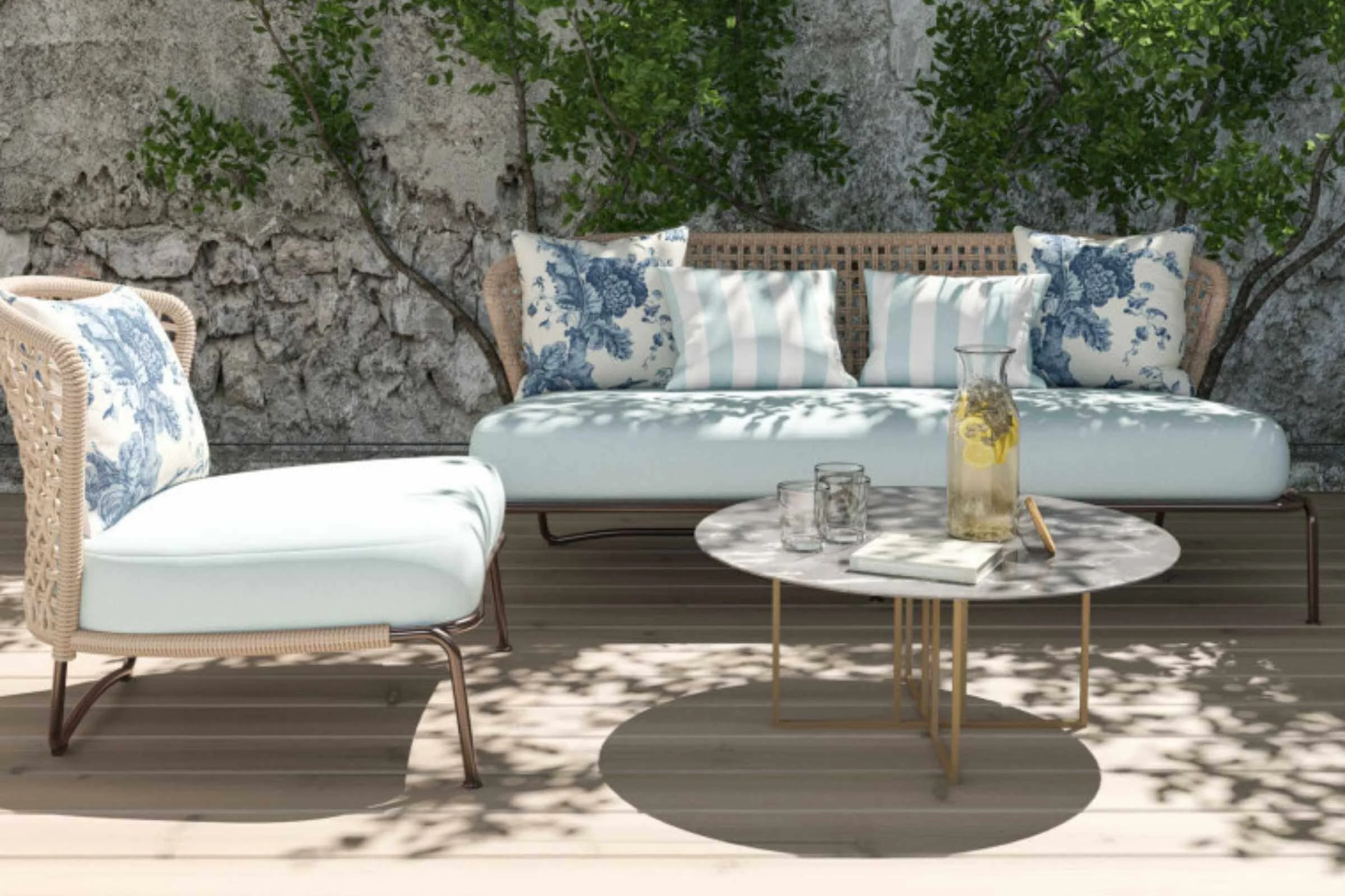 An example of Al Fresco Soft furnishings by Warner House - Patio Furniture made from metal and rattan, mineral blue fabric seat cushion, large blue and white toile fabric cushions, paired with mineral stripe smaller cushions.