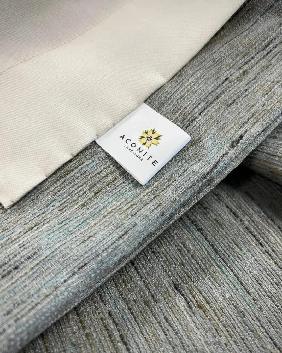 Close up image of the detailing behind one of the Aconite Interiors curtains - Aqua textured curtain withcream lining