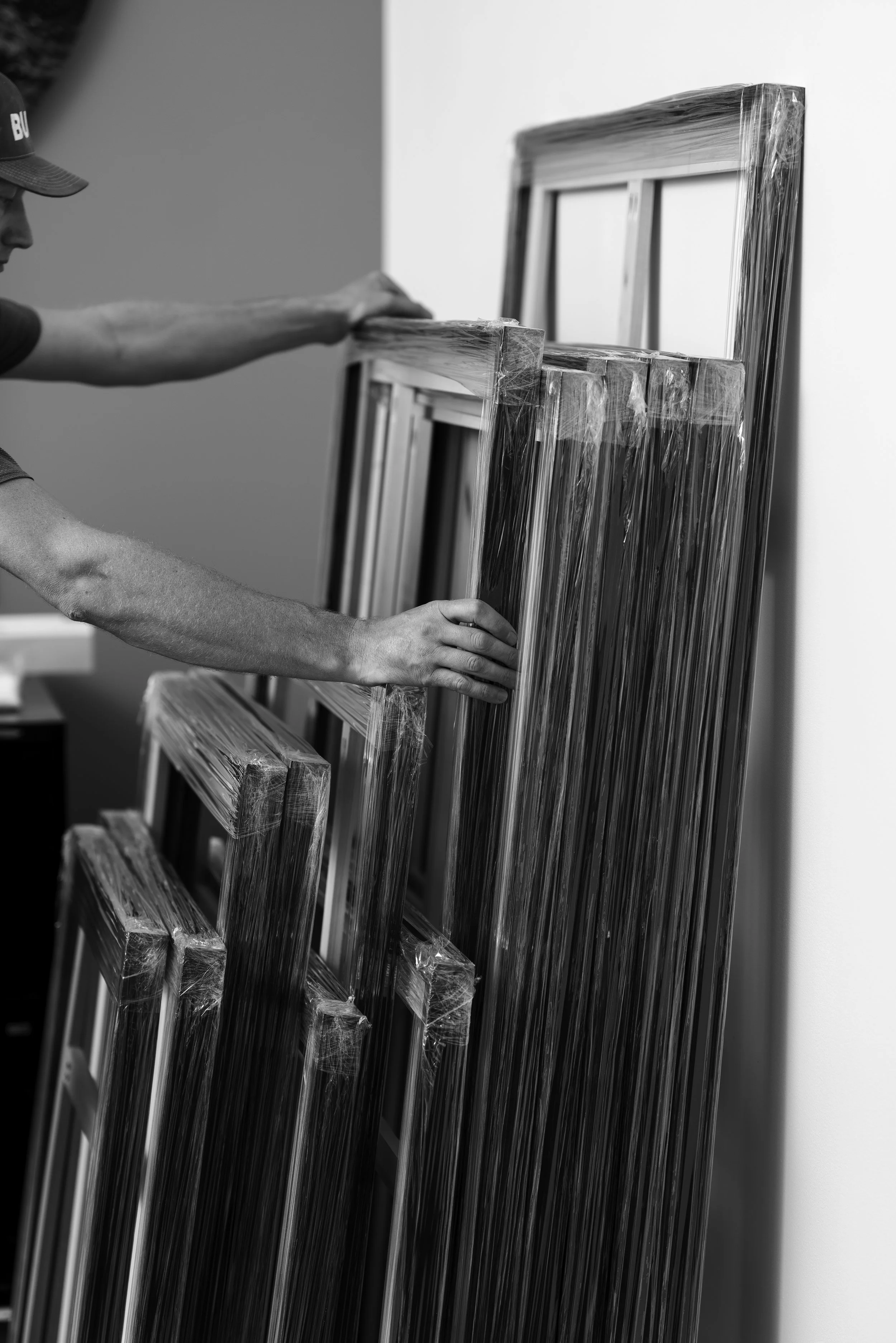 Person handling wrapped picture frames in a workshop.