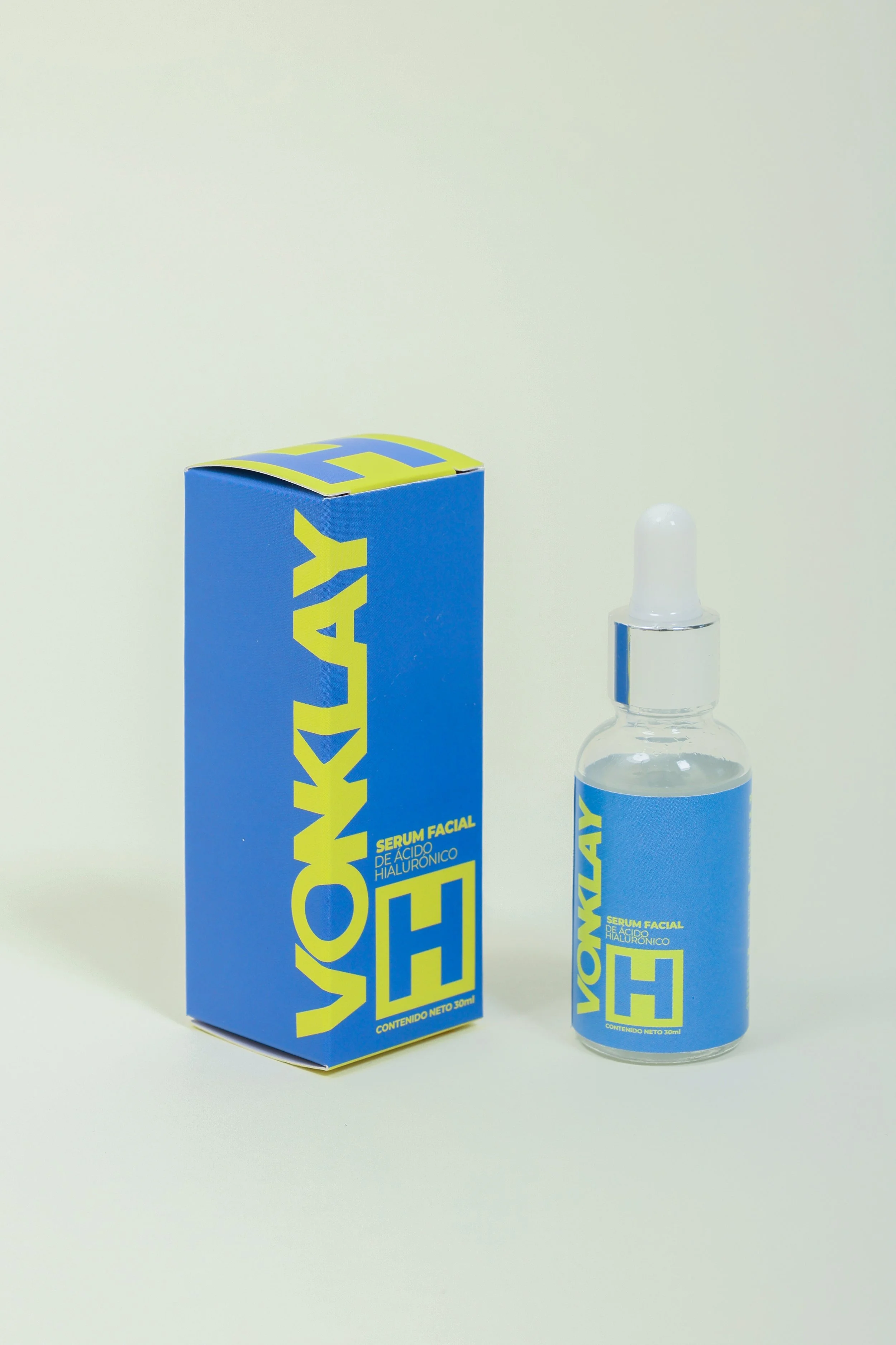 Botella y caja de suero facial con ácido hialurónico, de color azul y letras amarillas.