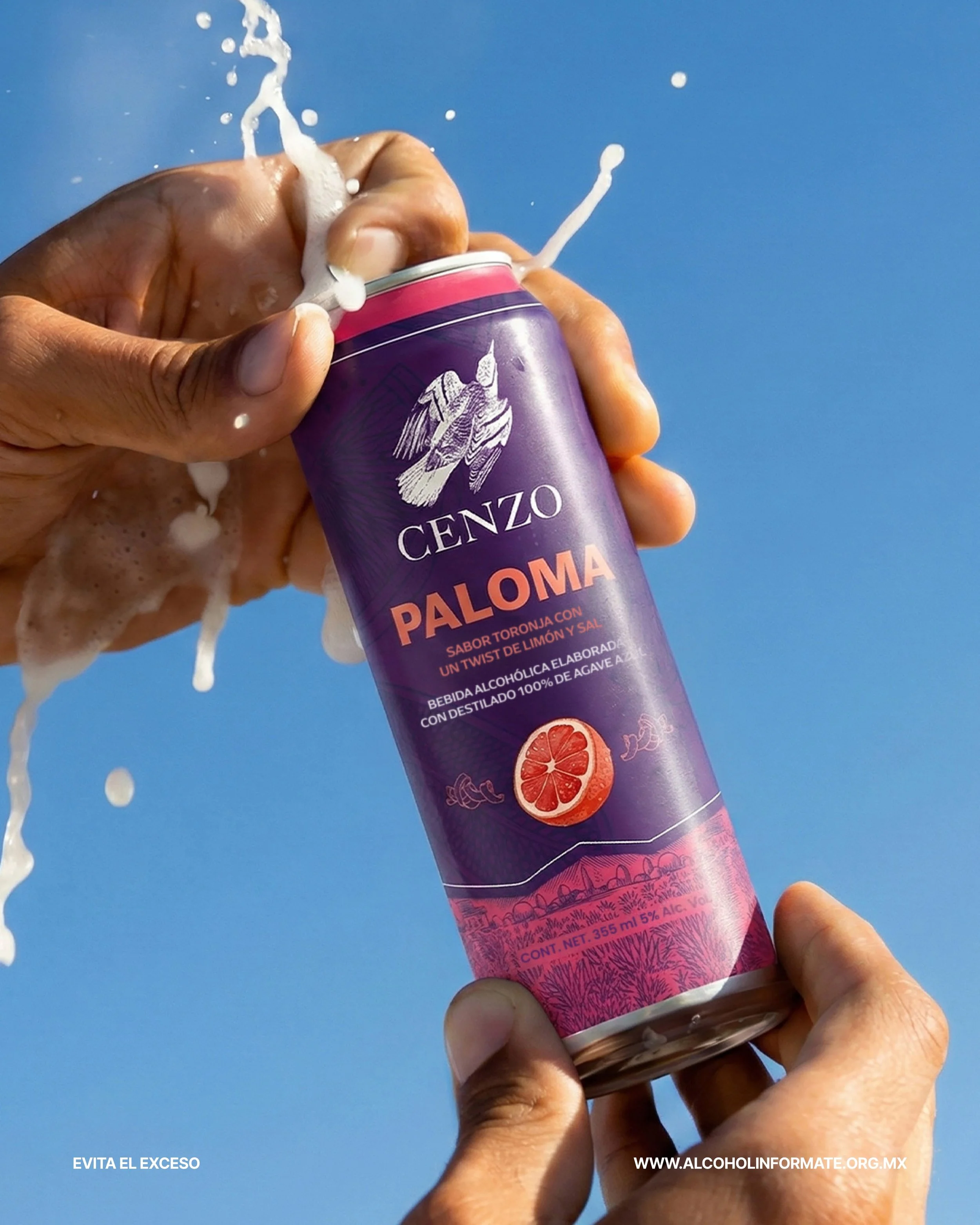 Una mano sostiene una lata de bebida alcohólica con sabor toronja, llamada 'Paloma' de la marca Cenzo, siendo abierta y con espuma. El fondo es un cielo azul.