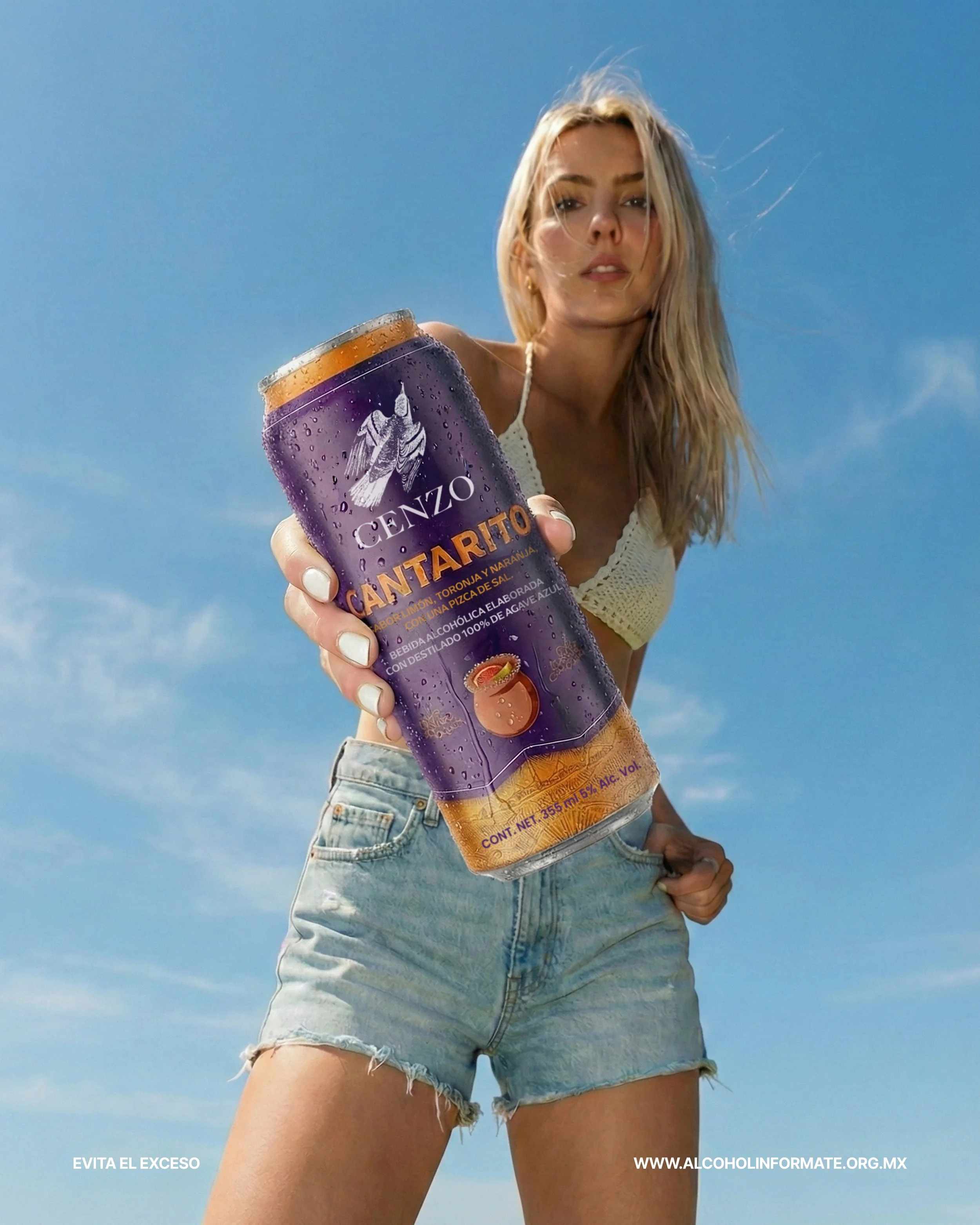 Joven mujer con blusa blanca y pantalones cortos de mezclilla sostiene una lata de Cántaro de sabor a naranja y limón en un día soleado con cielo azul.