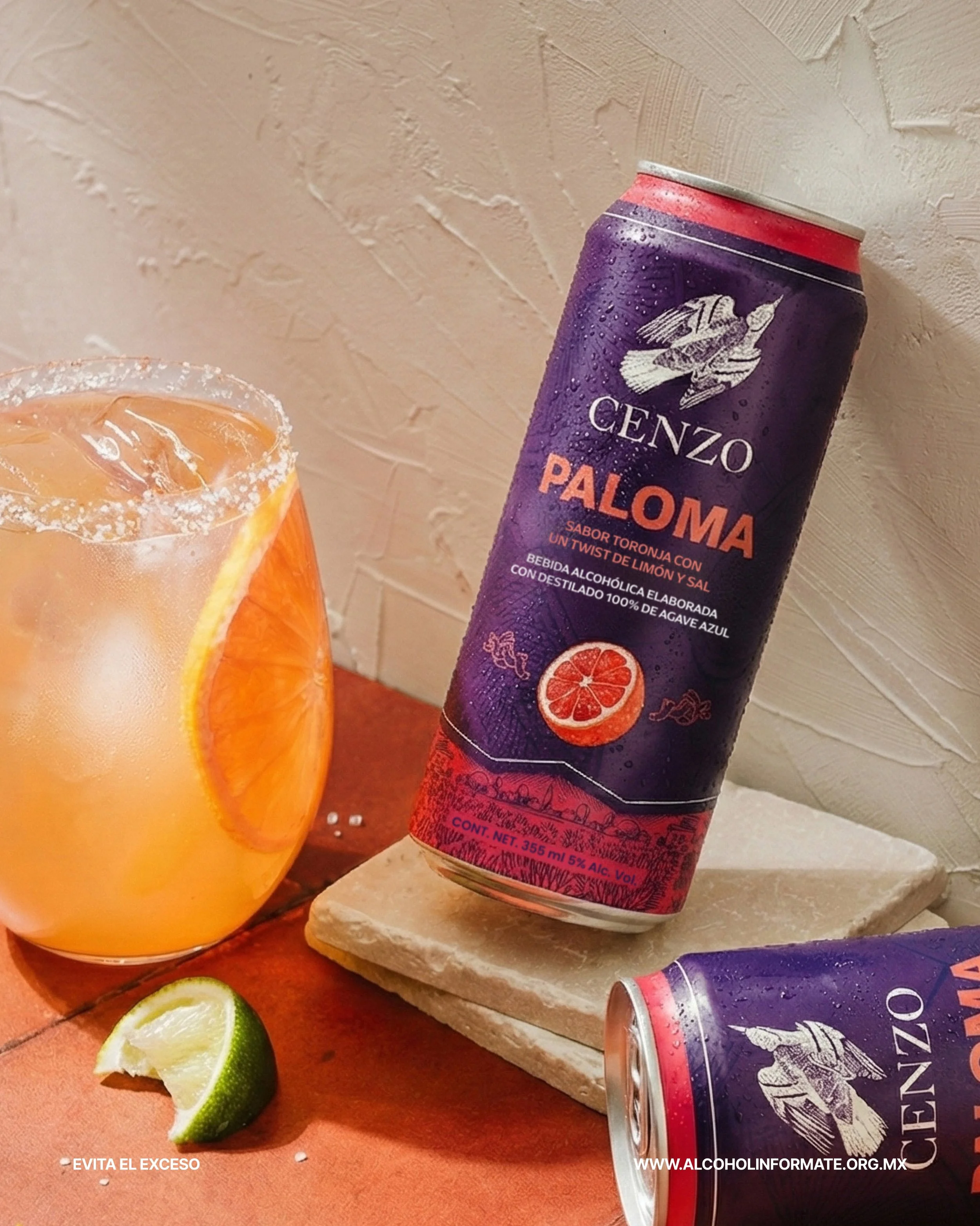 Lata de bebida alcohólica Genz Paloma con sabor a toronja, a un lado un vaso con una bebida de color anaranjado, una rodaja de limón, y una rodaja de naranja en la bebida.