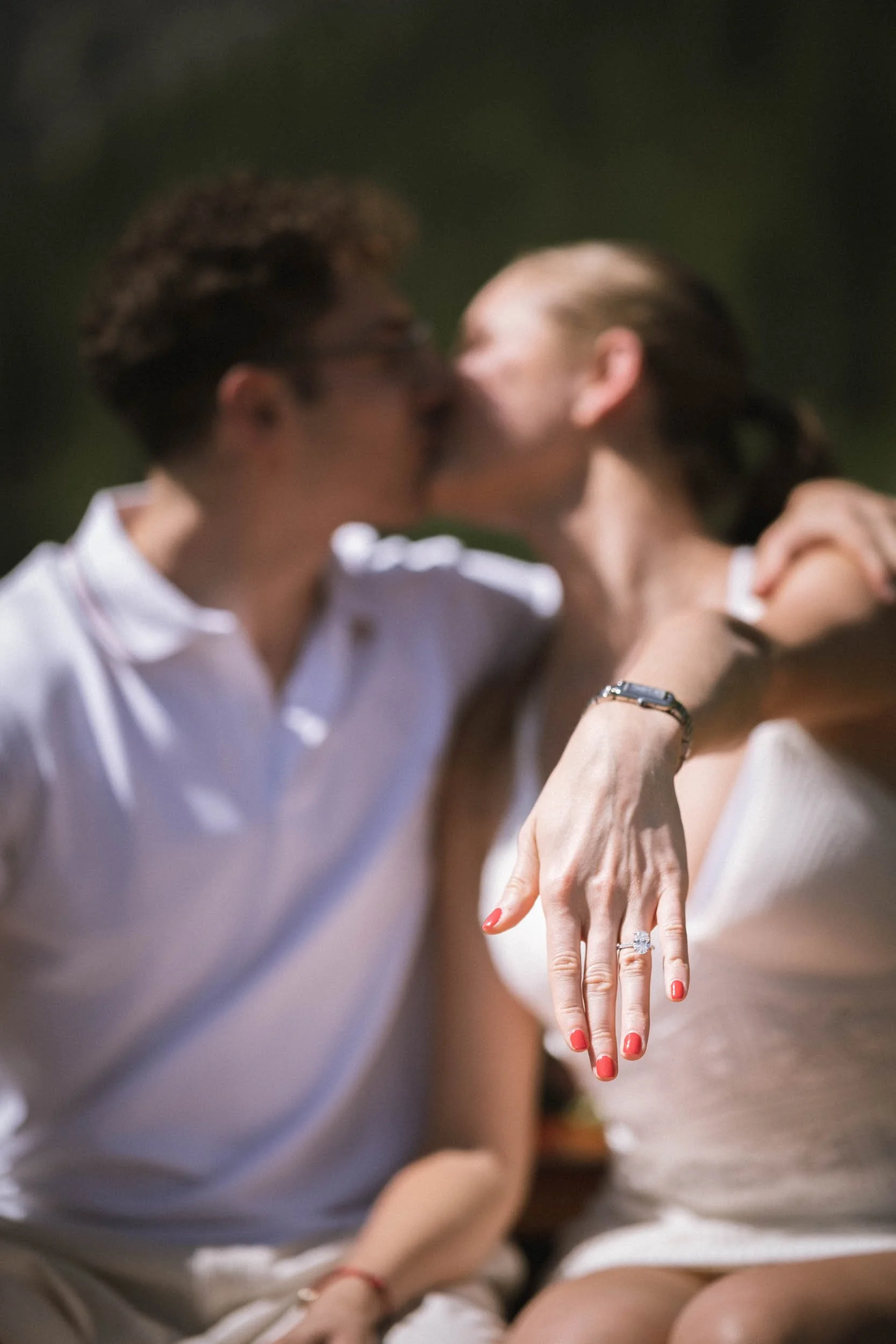 Ein verliebtes Paar beim Küssen, die Frau zeigt einen Verlobungsring auf ihrer Hand.