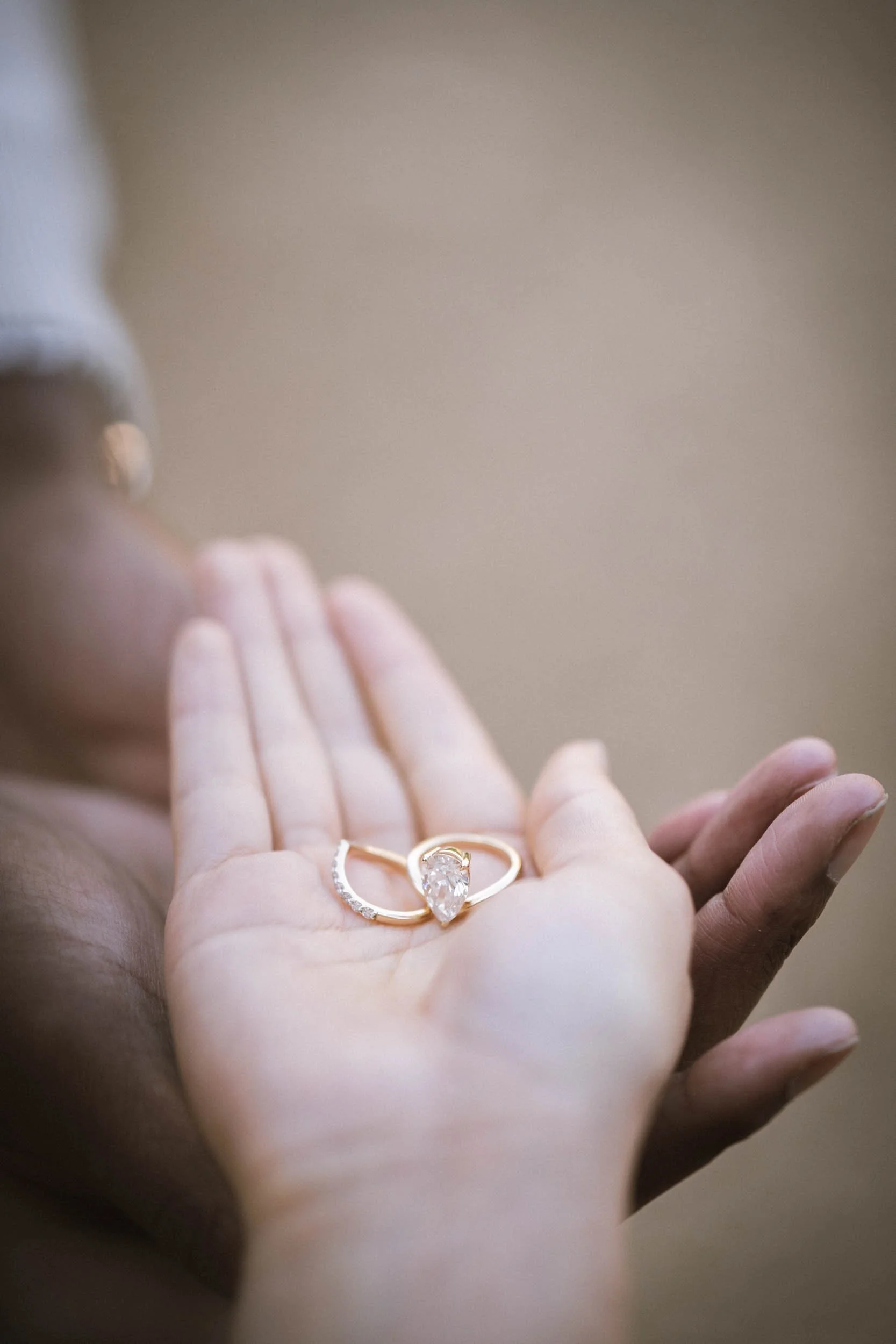 Nahaufnahme eines Handrings mit einem großen, birnenförmigen Diamanten, umgeben von kleineren Edelsteinen.