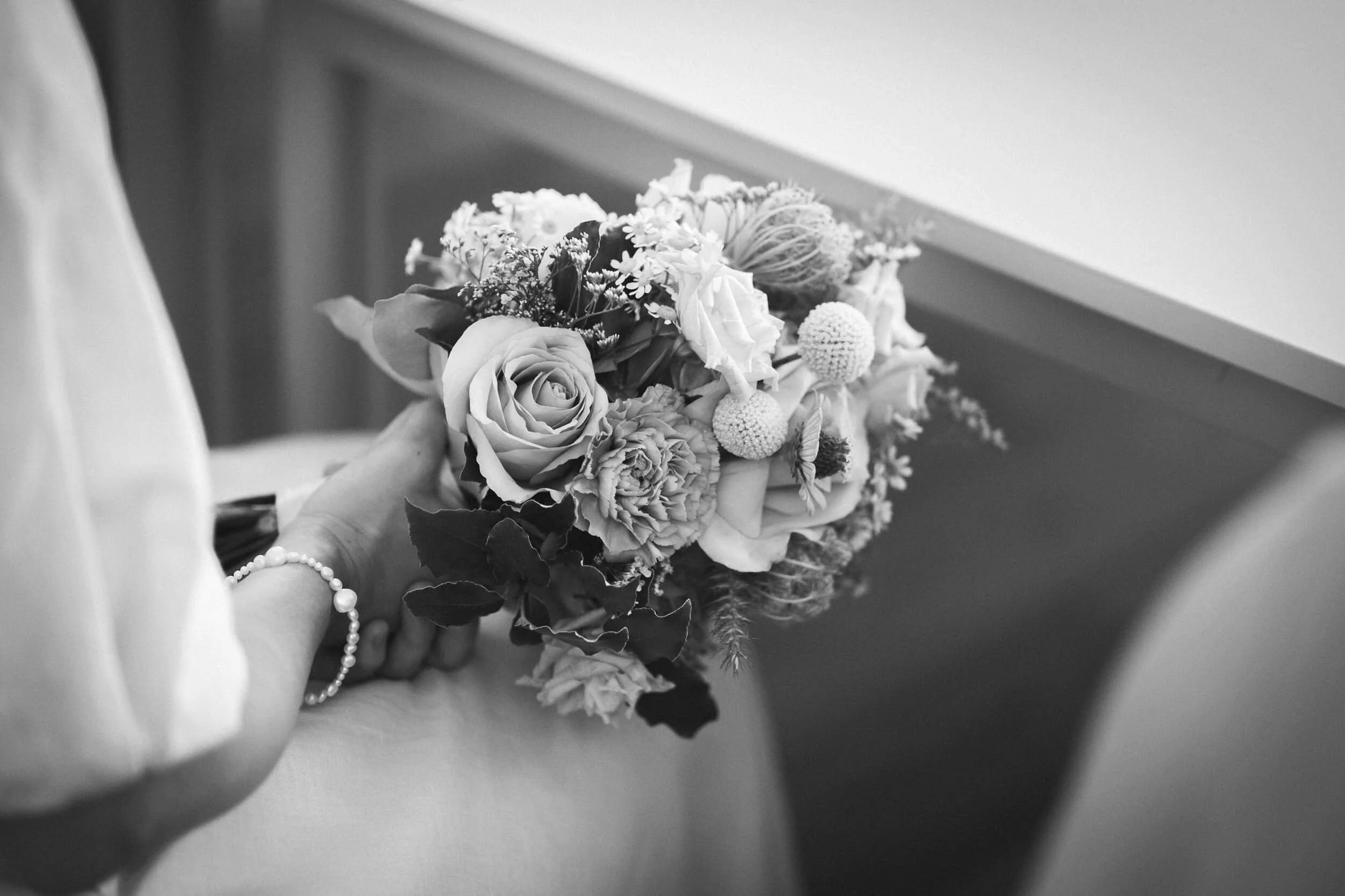 Schwarz-weiß-Bild einer Frau, die einen Blumenstrauß hält, vermutlich bei einer Hochzeit.