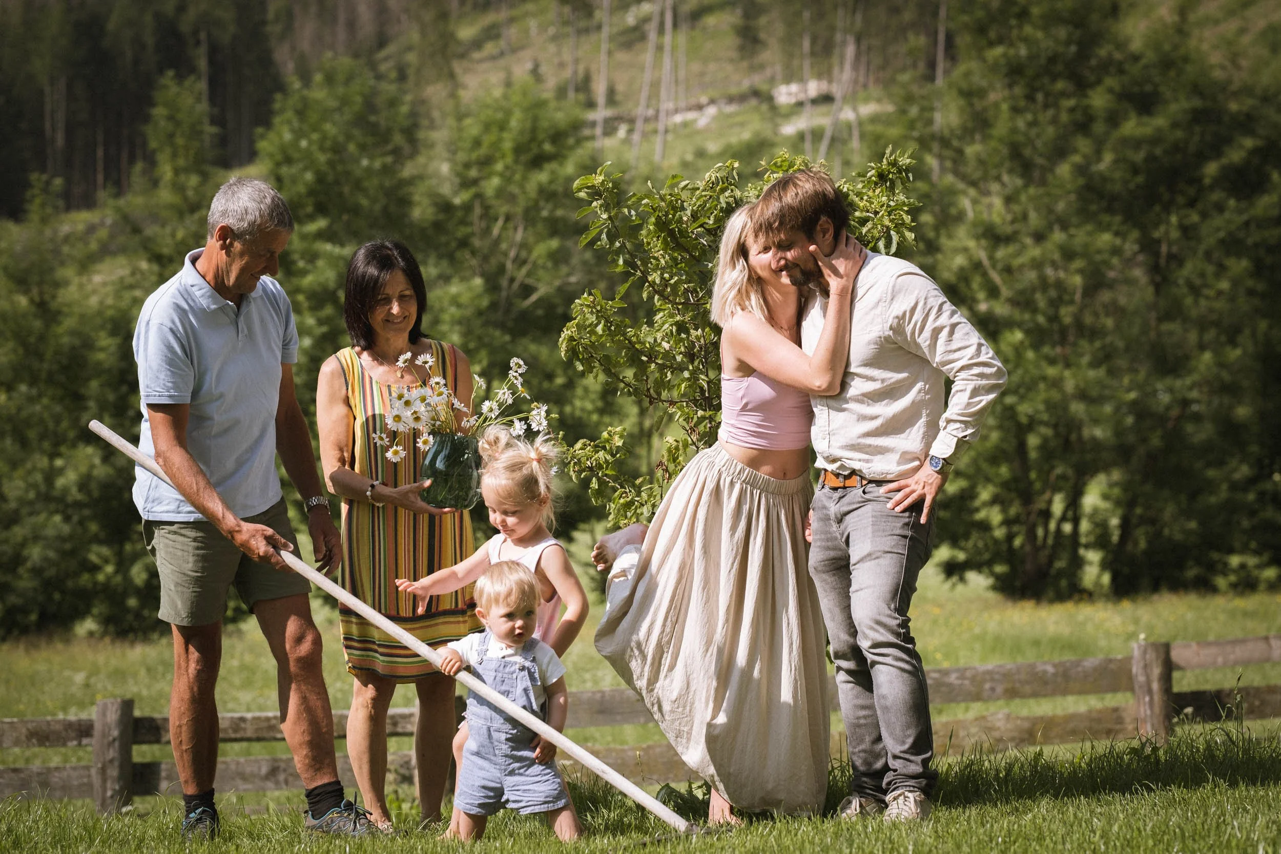 Eine Gruppe Menschen, darunter Kinder, feiern draußen in der Natur, wobei ein Paar im Mittelpunkt steht, umgeben von anderen Familienmitgliedern.