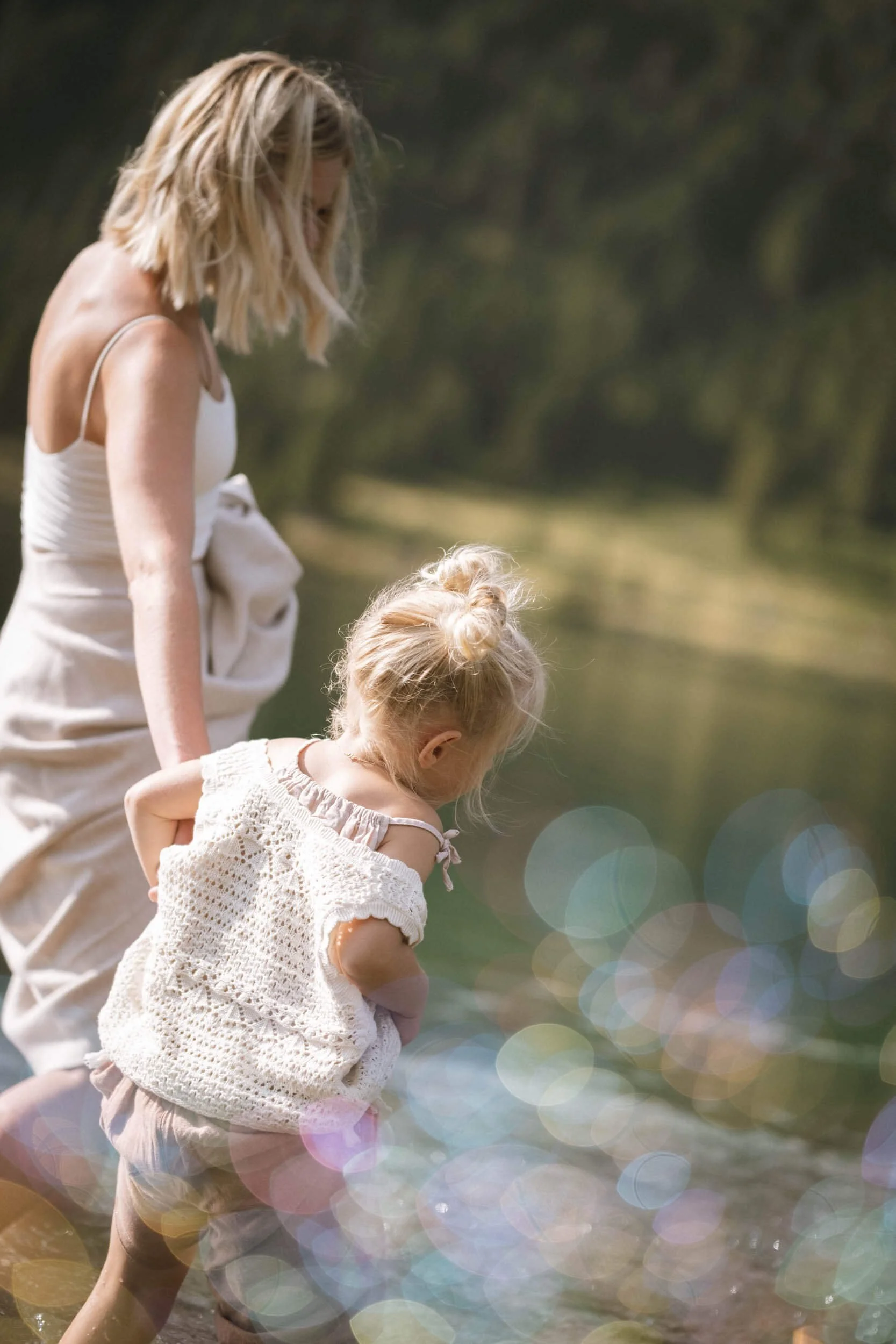 Eine Frau mit einem Kind am Wasser, beide schauen in den Fluss.