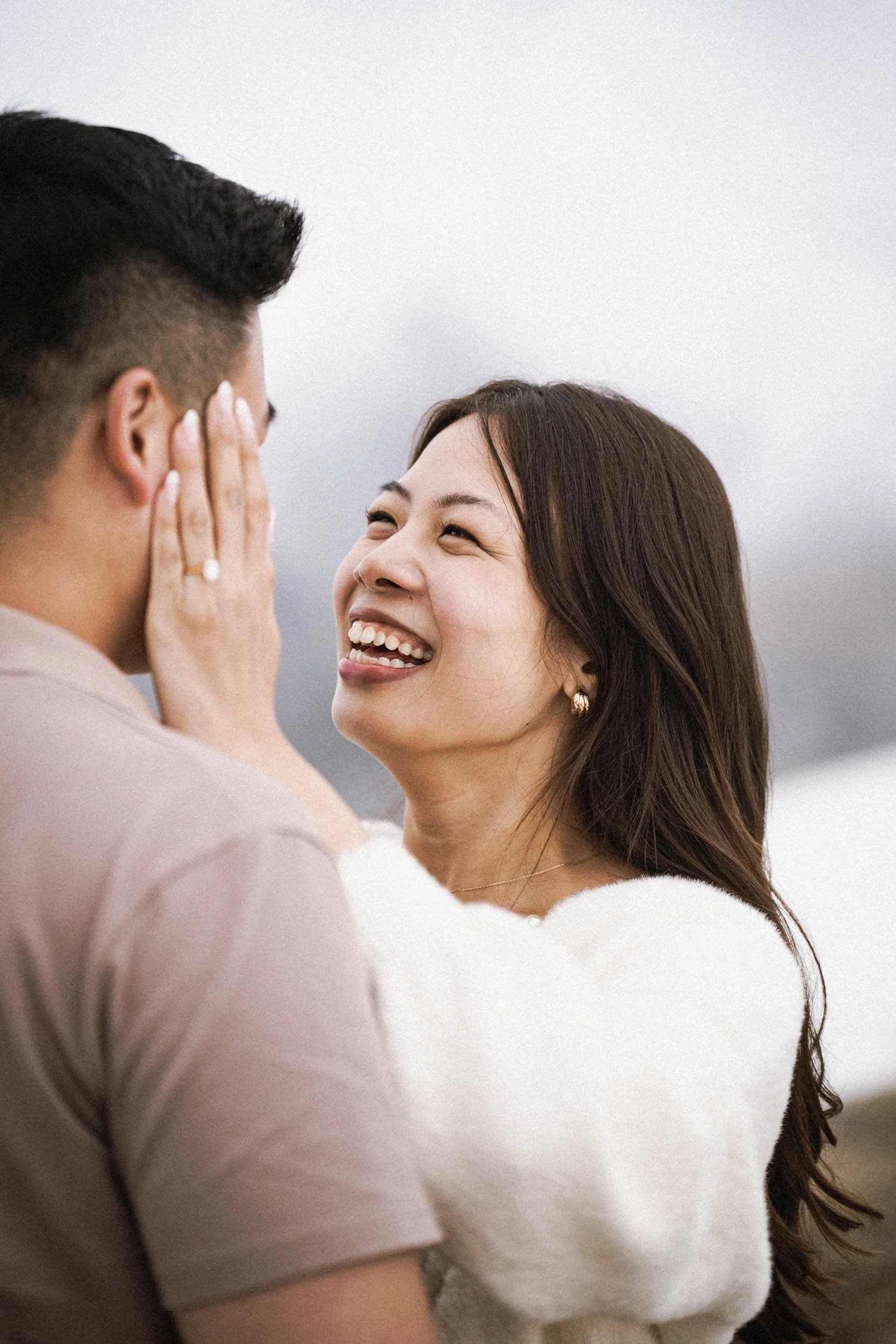 Ein Mann und eine Frau schauen sich verliebt an, die Frau lächelt glücklich, während sie den Mann zärtlich berührt.