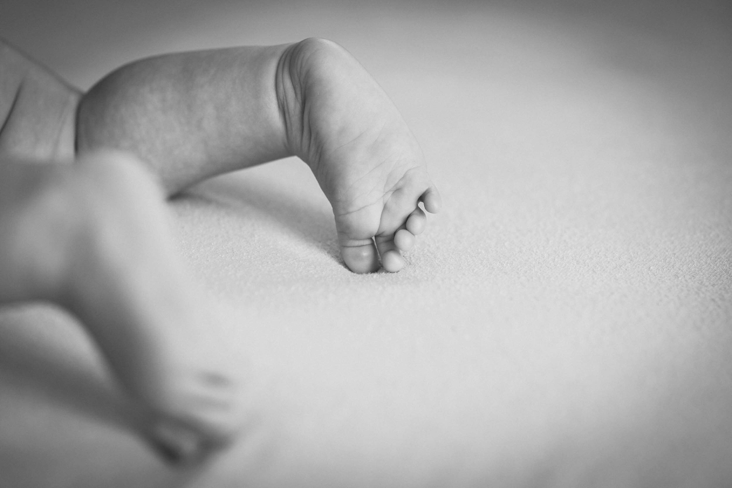 Nahaufnahme einer kleinen Hand, die auf einer glatten Oberfläche kratzt, in Schwarz-Weiß.