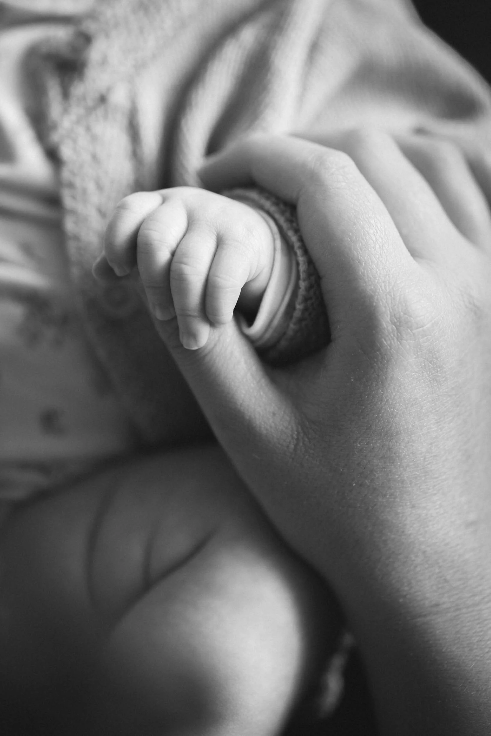 Nahaufnahme einer Hand, die eine kleine Kinderhand hält, in Schwarz-Weiß.