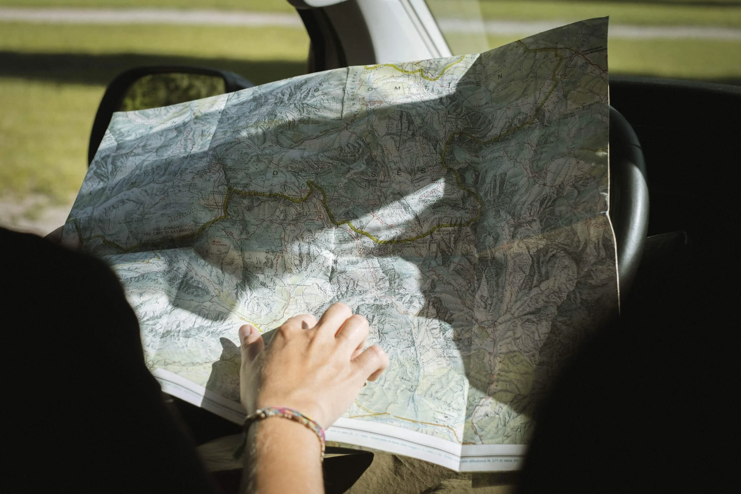 Nahaufnahme einer Person, die eine große Landkarte im Auto betrachtet.