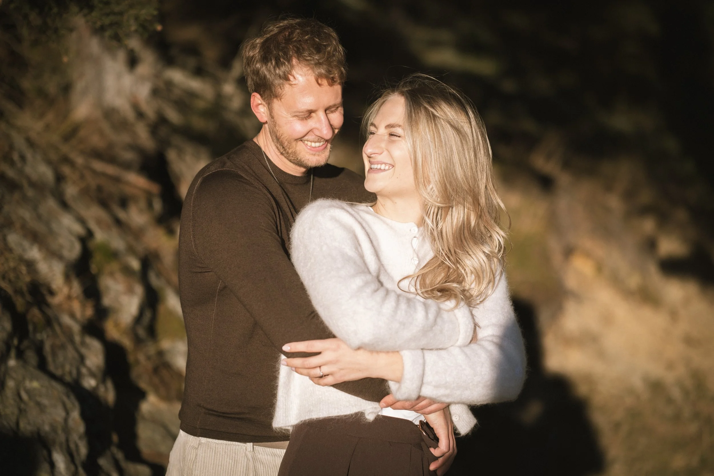 Ein glückliches Paar umarmt sich bei Sonnenuntergang im Freien.