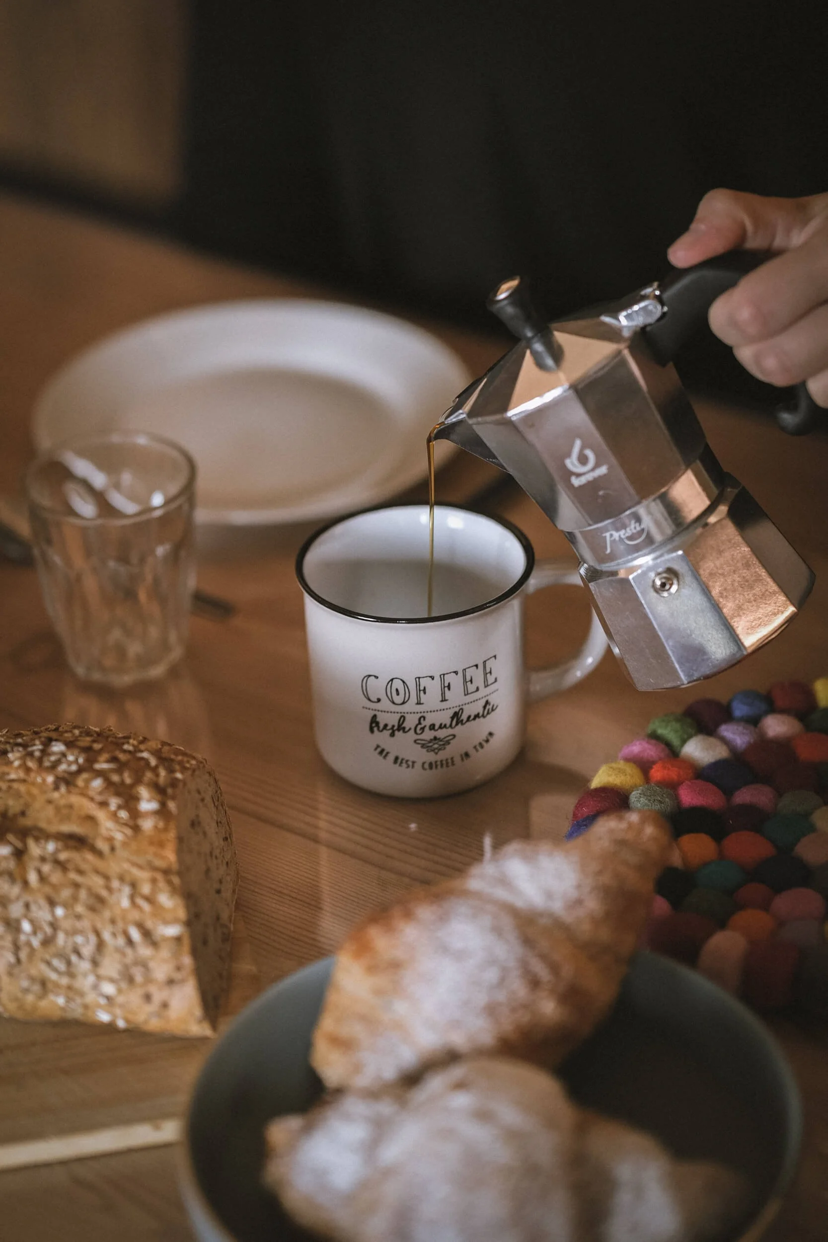 Person schüttet Espresso aus einer Mokkakanne in eine Tasse
