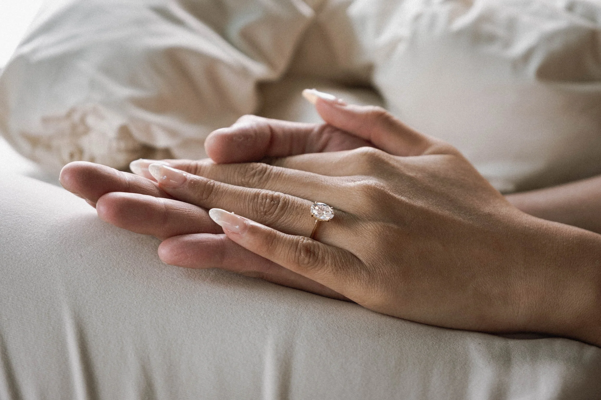 Nahaufnahme von Händen mit einem Verlobungsring mit großem Diamanten