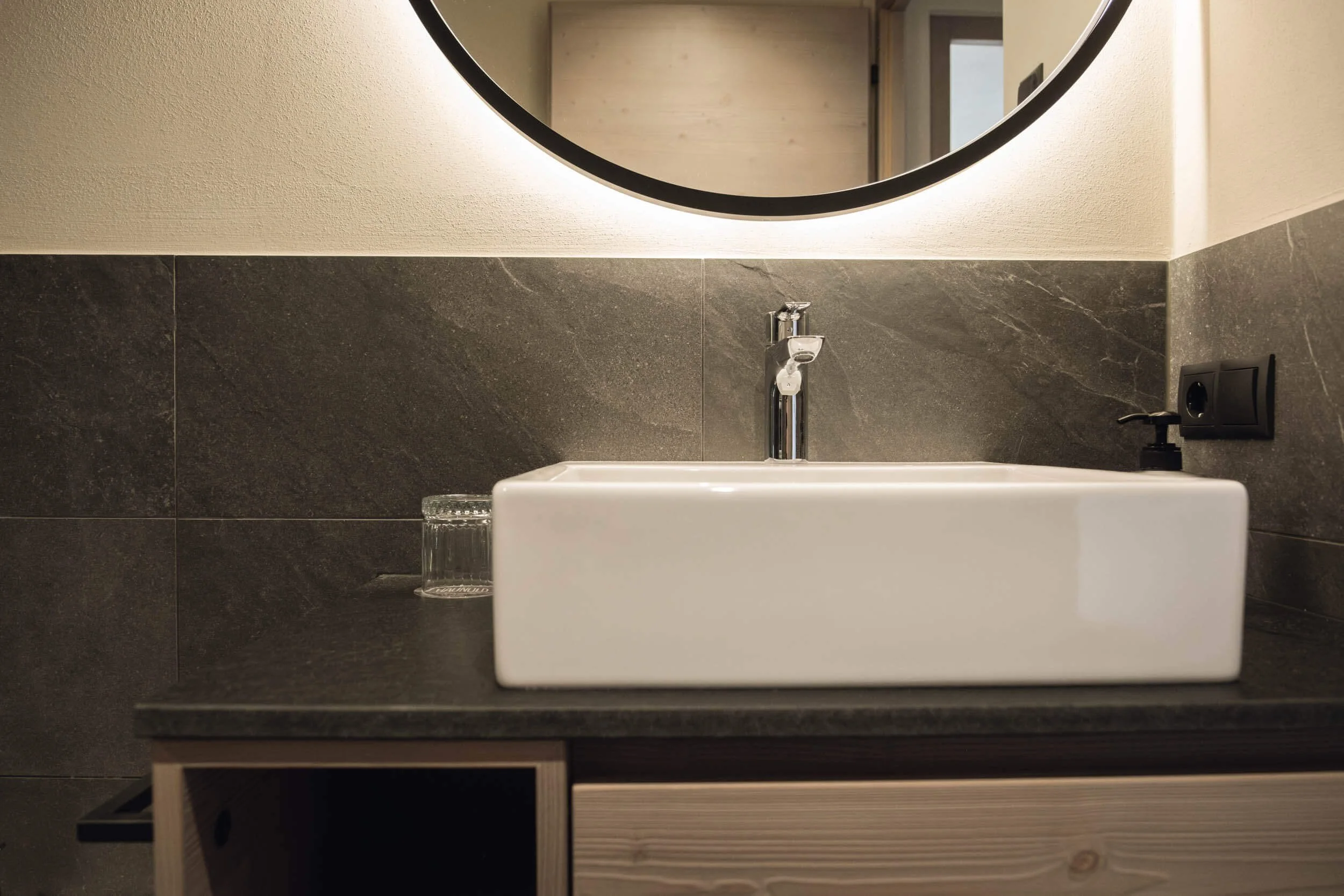 Waschbecken mit Spiegel und Waschmittelspender in einem Badezimmer