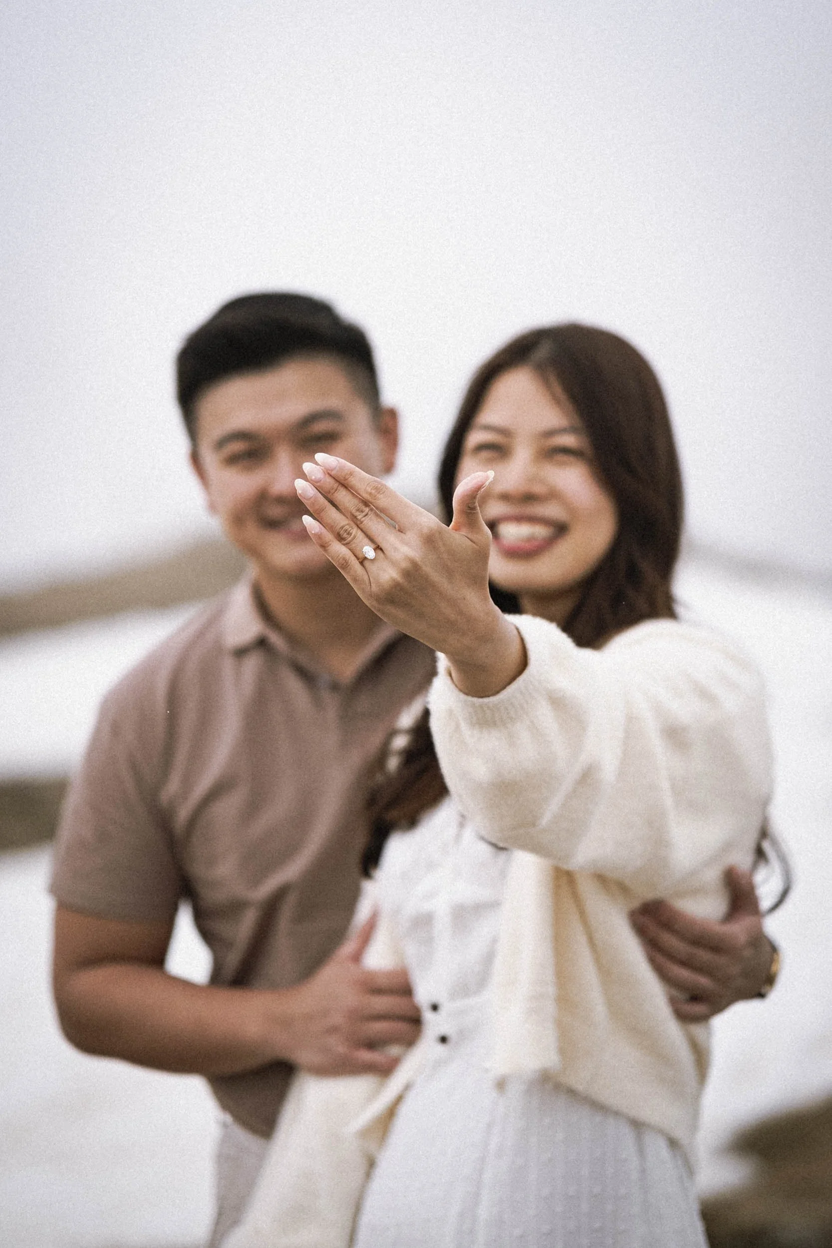 Ein glückliches Paar zeigt ein Verlobungsring an einem gemeinsamen Finger.