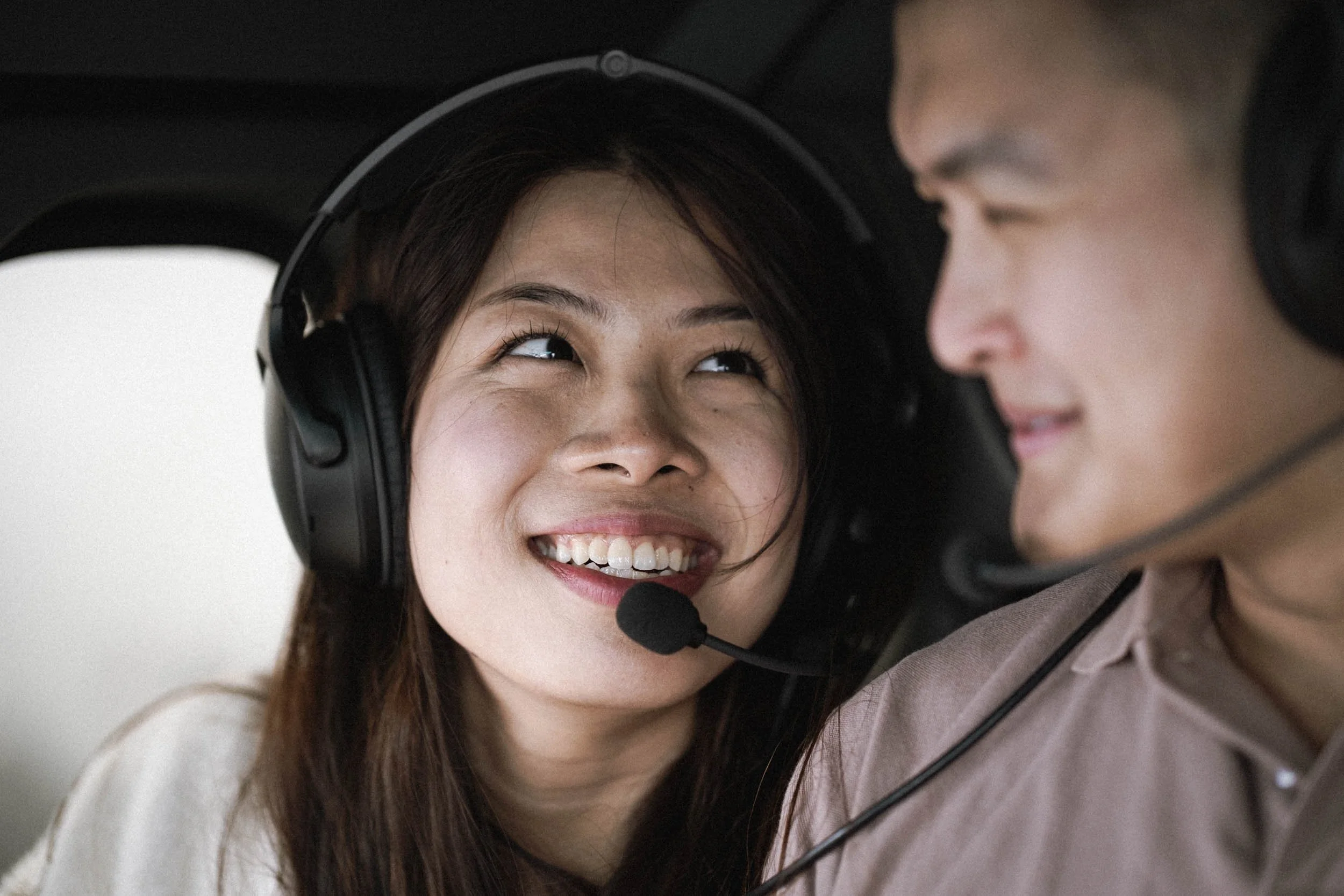 Ein Mann und eine Frau sitzen in einem Hubschrauber, beide tragen Headsets für die Kommunikation.