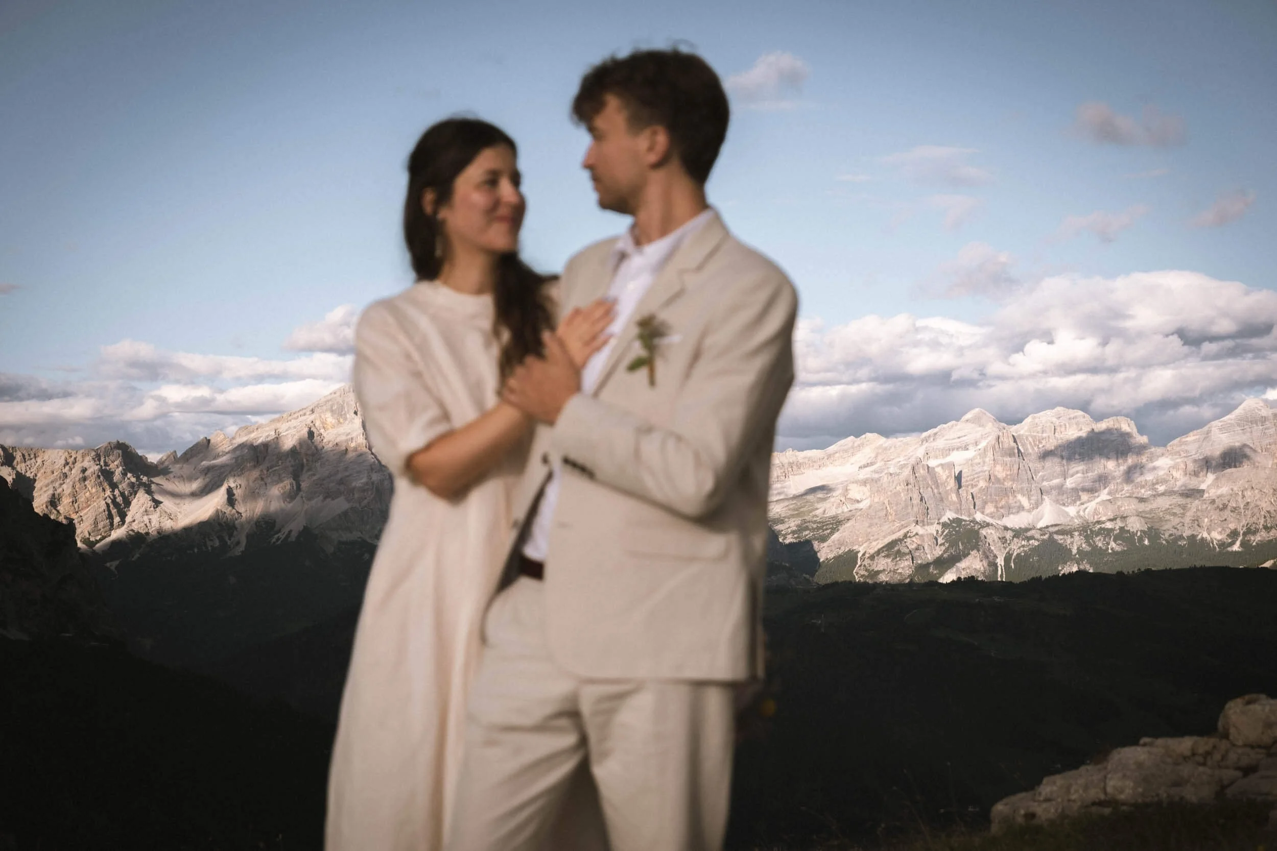 Ein verliebtes Paar in eleganter Kleidung, das in den Bergen steht und sich ansieht.