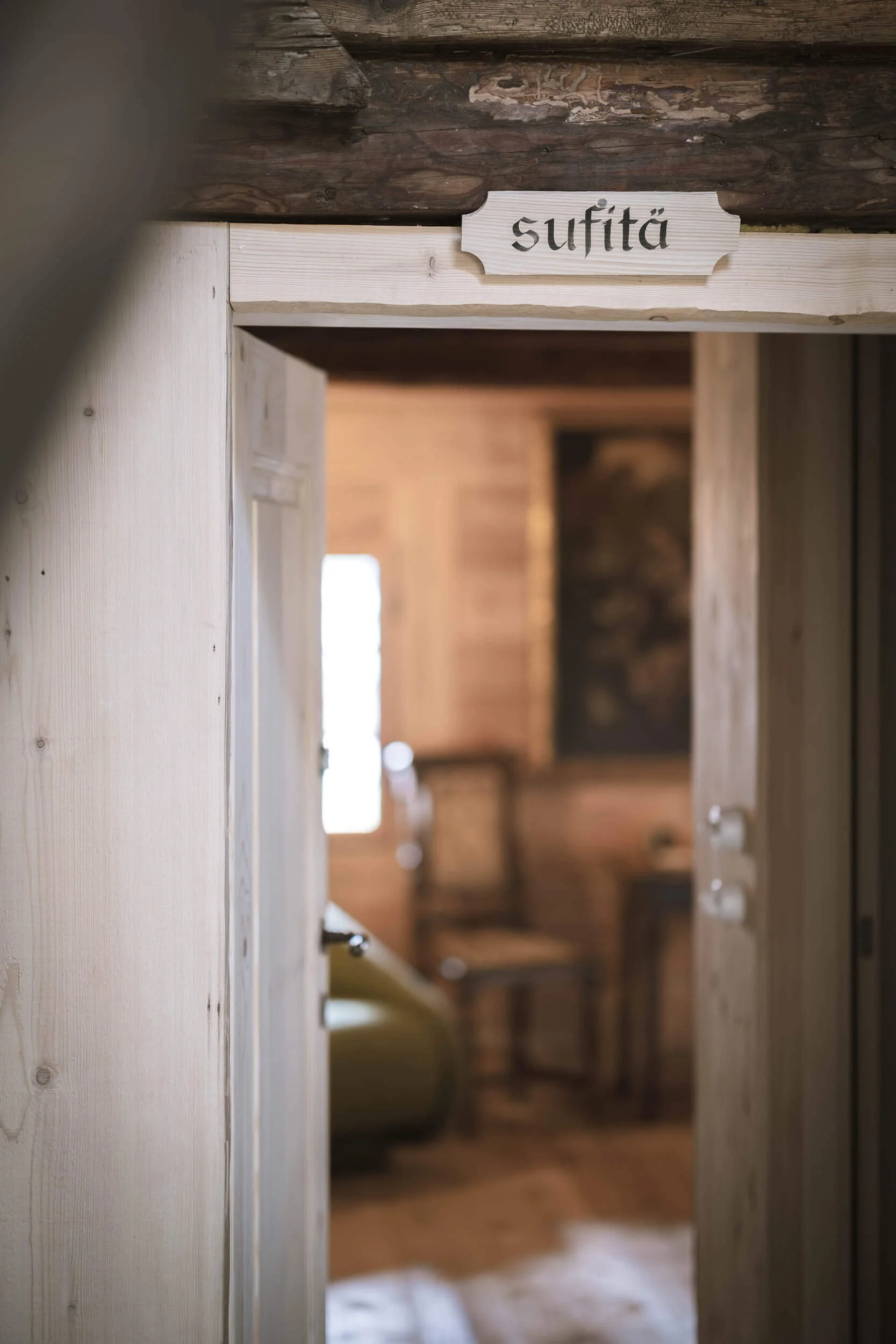 Blick durch eine Tür in einen rustikalen Raum mit Holzinterieur, Holzmöbeln und einem Fenster.