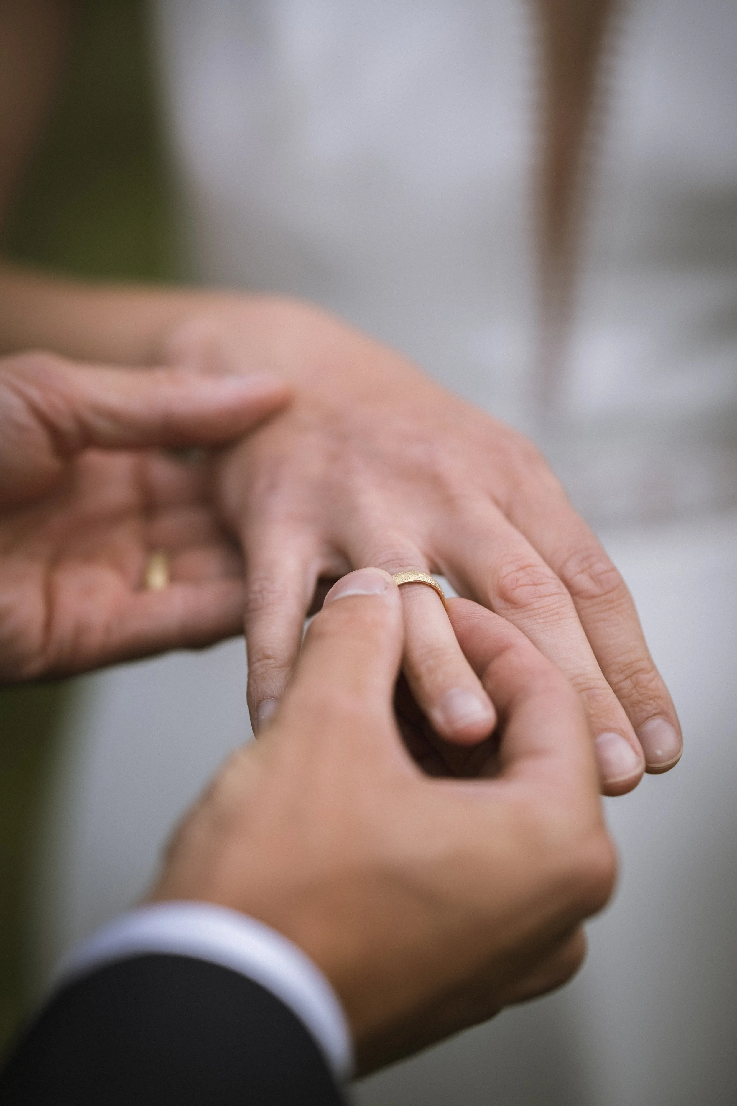 Ein Mann steckt einer Frau einen Ehering am Finger an, Nahaufnahme, symbolisiert Heirat oder Verlobung.