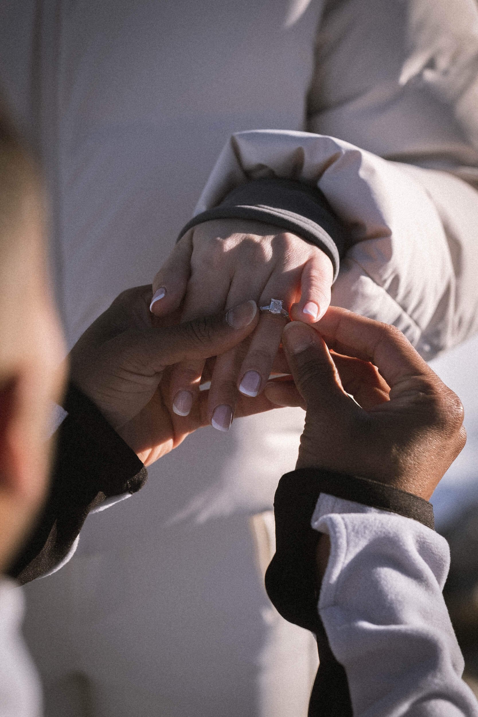 Jemand steckt einem anderen einen Verlobungsring an den Finger.