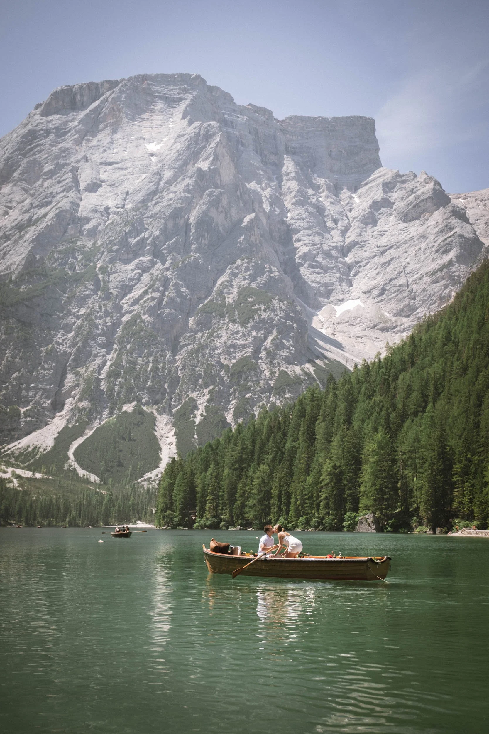 Zwei Frauen im Boot auf einem See mit hohen Bergen und einem Wald im Hintergrund.