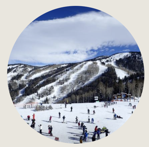 Casper- A bright winter day at a Wyoming ski resort shows skiers and snowboarders scattered across snowy slopes beneath a vivid blue sky. Snow-covered mountains rise in the distance.