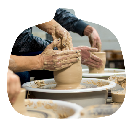 People shaping clay pots on pottery wheels during a pottery class.