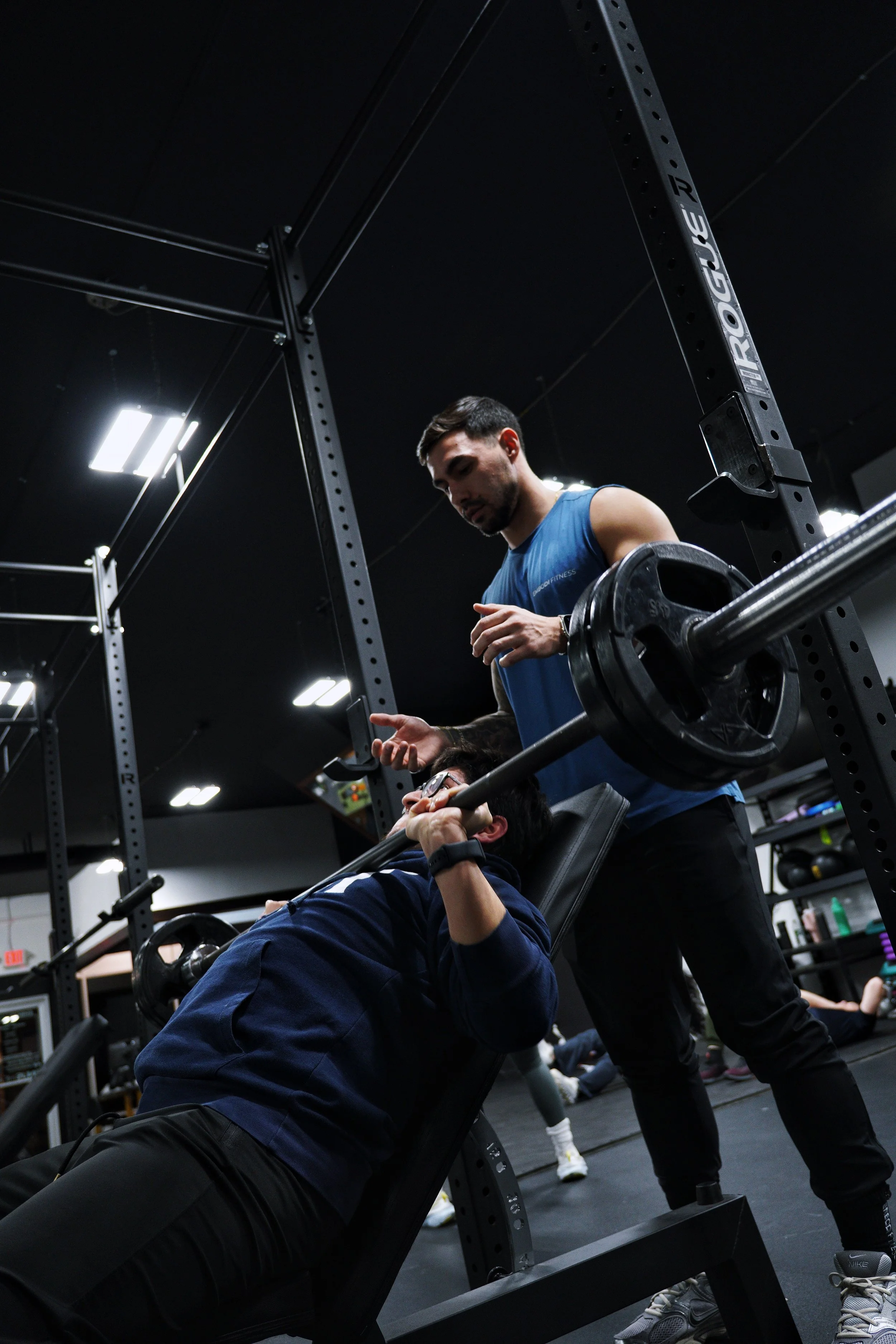 An EMBODI Fitness trainer spotting a member doing an incline bench press.