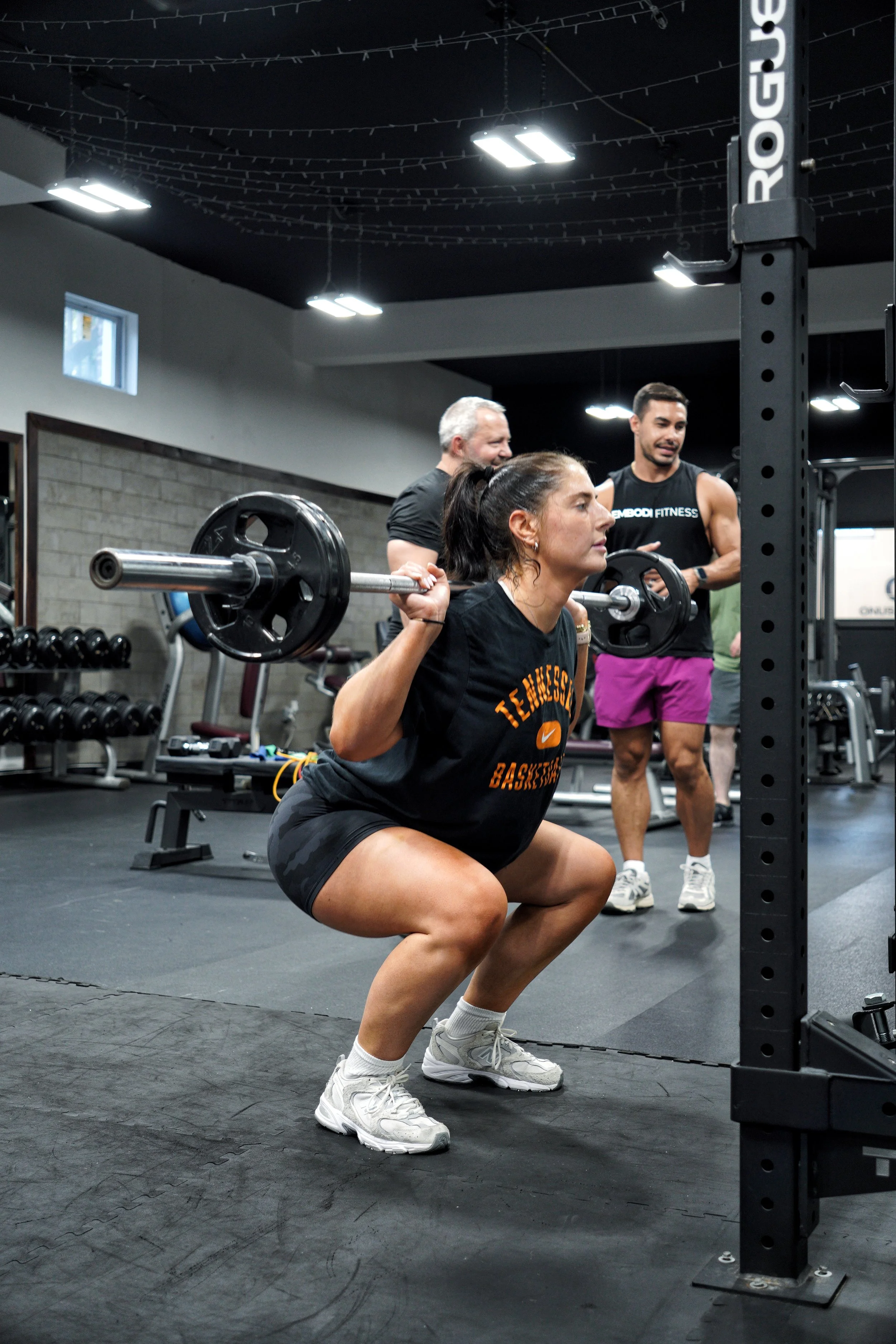 Member performing a barbell squat during a coached strength session at EMBODI Fitness, showcasing technique, progression, and form-focused semi-private training.