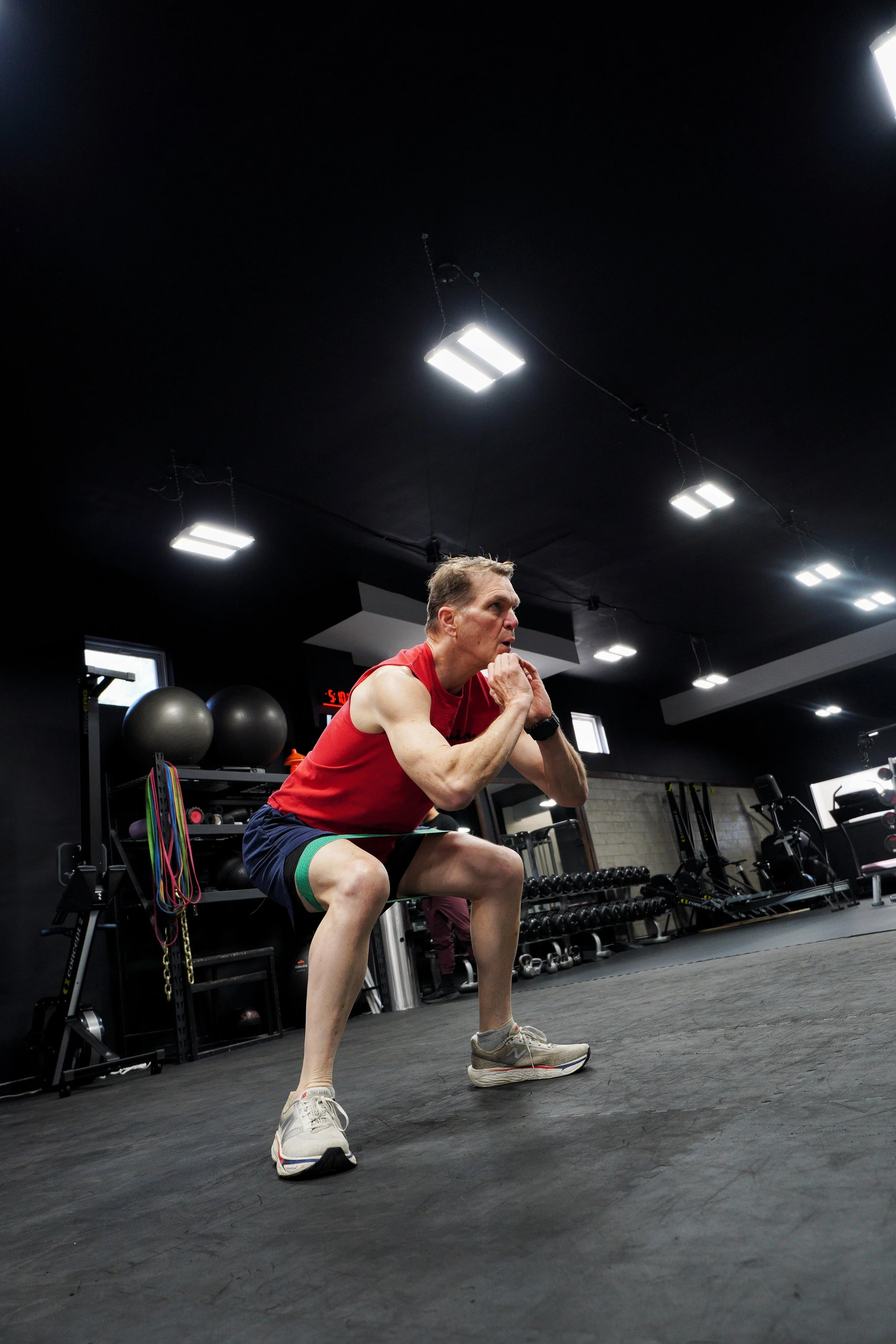 EMBODI Fitness coach supporting a client through a dumbbell bench press, providing form correction and encouragement during a personalized training session.