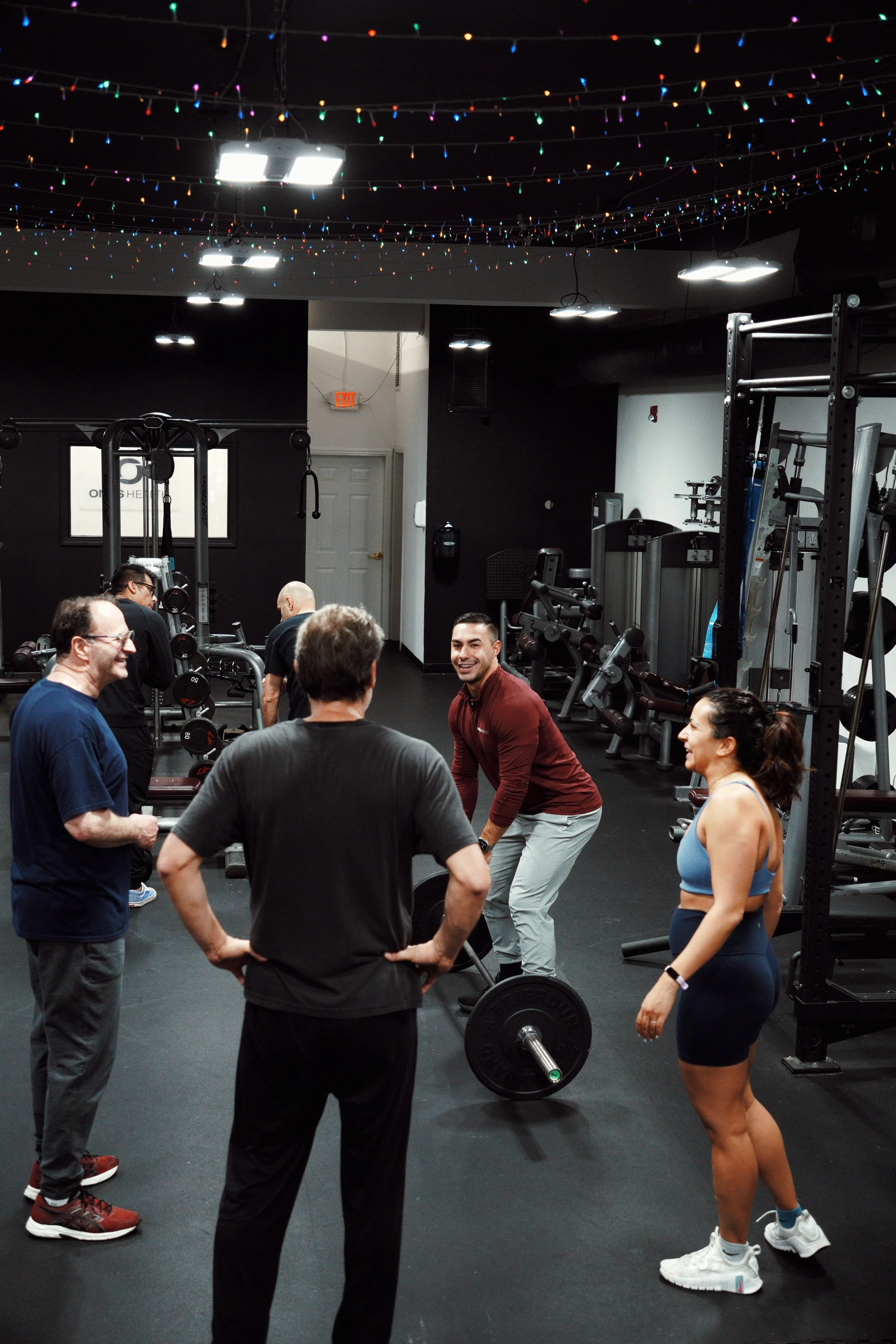 Small-group strength training session at EMBODI Fitness in Caldwell, NJ, with a coach guiding members through deadlift technique in a supportive semi-private format.