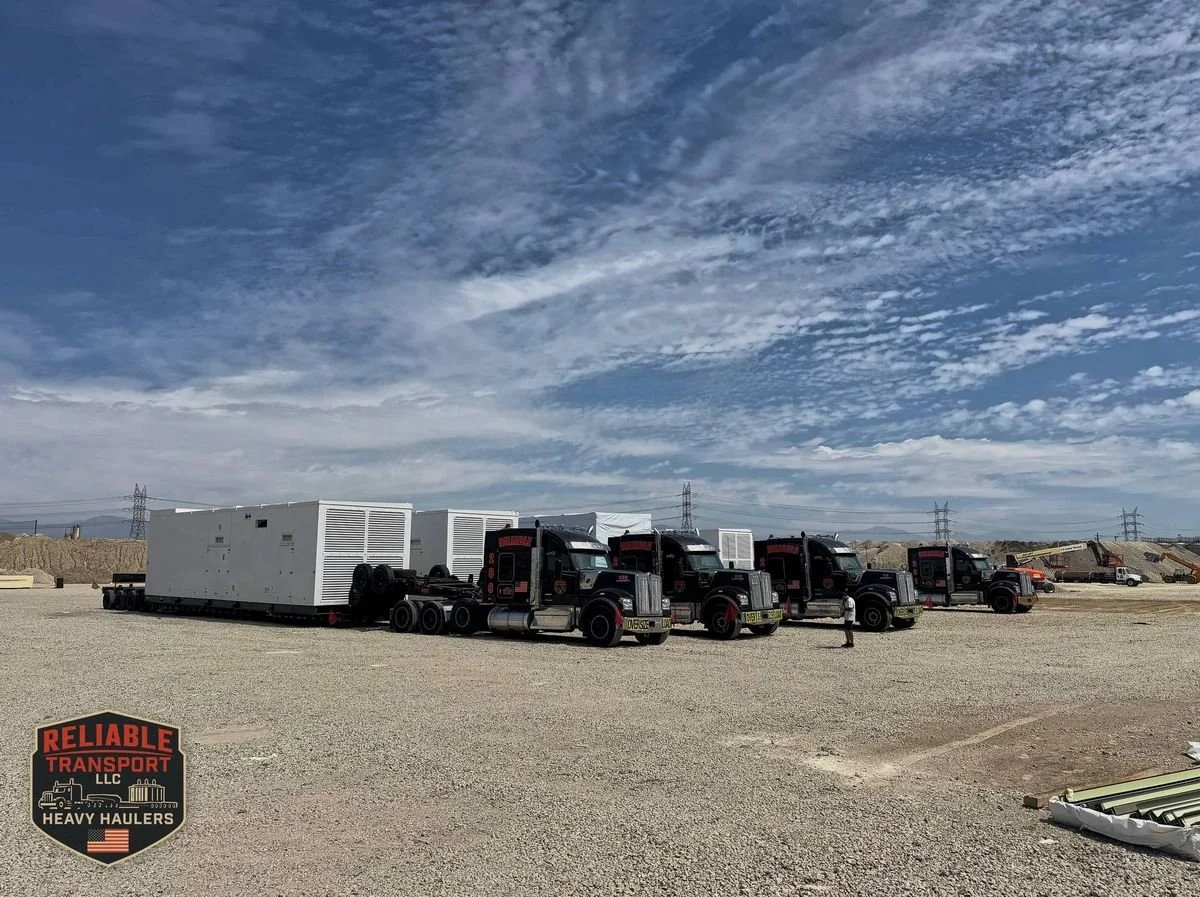 Four black Reliable Transport trucks lined up on a gravel site with large white genset enclosures on trailers, power lines behind