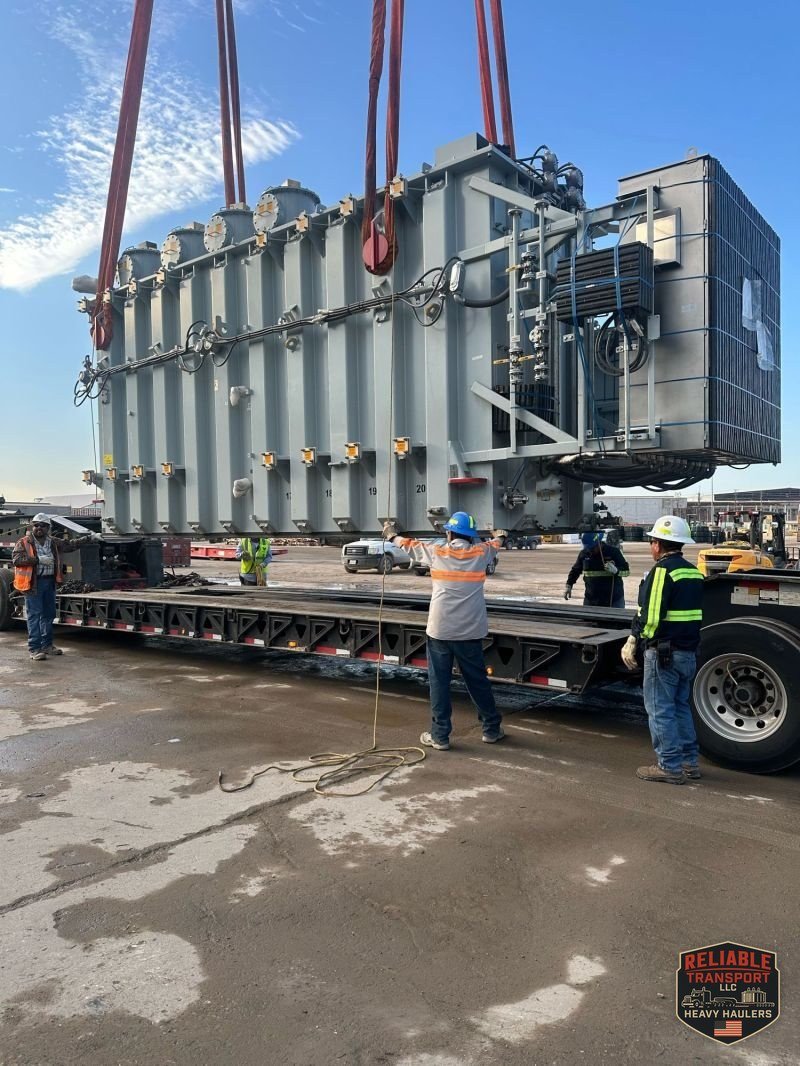 The 160,000 lb power transformer hanging from red crane slings over our trailer in Obetz, Ohio, as crew members work