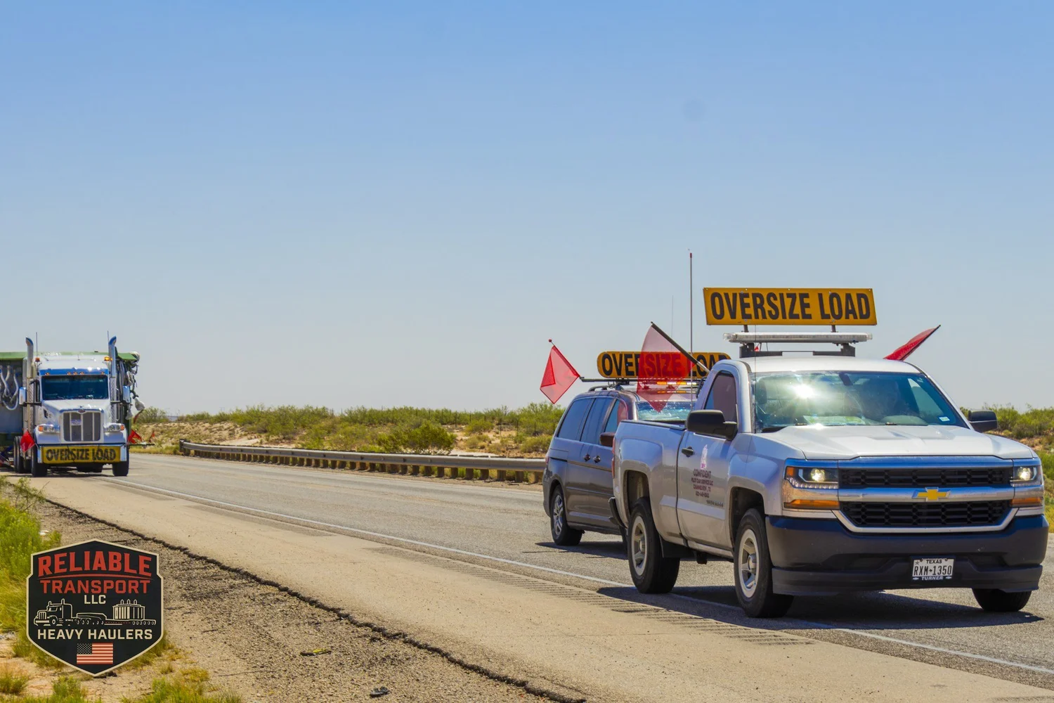 Escort pickup with an OVERSIZE LOAD sign leading a wide load along a desert highway