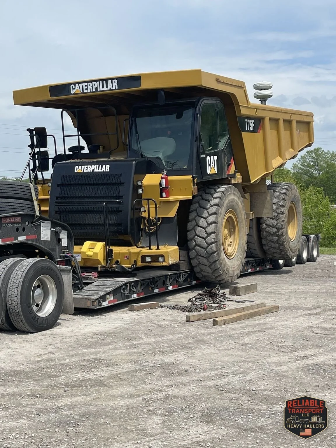 Close view of the haul truck and its large tires chained down on the trailer deck