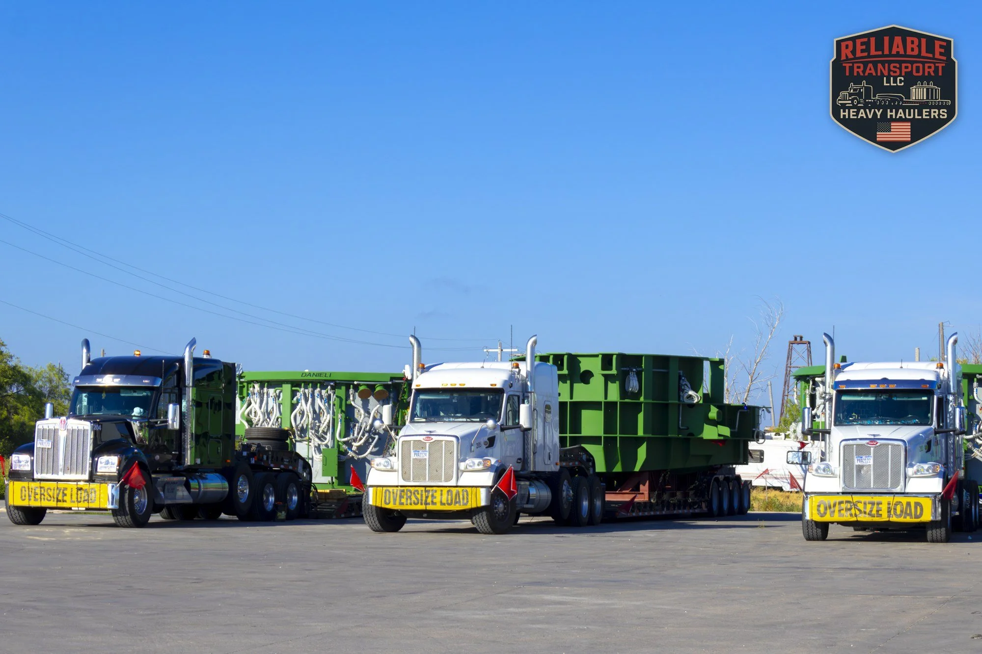 Three heavy haul trucks lined up side by side, each with a wide green load on a multi axle trailer and an OVERSIZE LOAD banner on the bumper