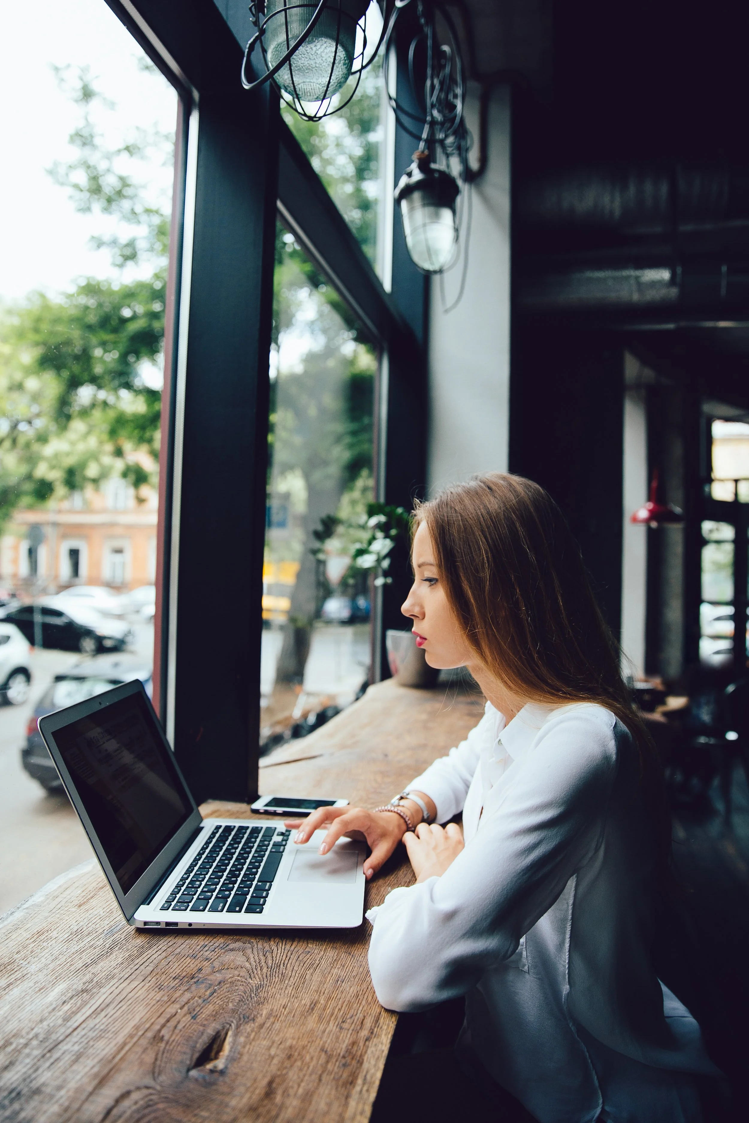 side-view-charming-thoughtful-businesswoman-using-laptop-while-sitting-cafe.jpg