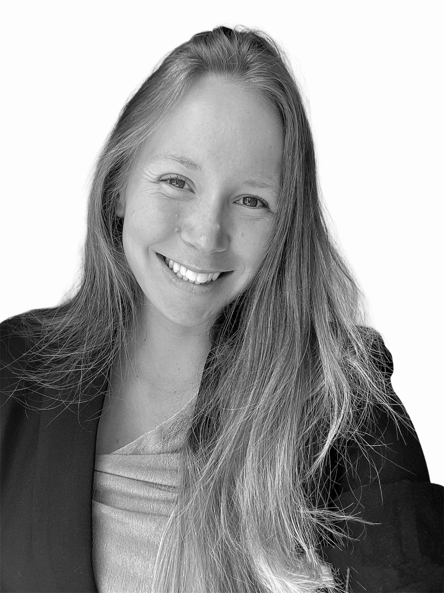 A smiling woman with long hair, wearing a blazer and top, in a close-up black and white portrait.