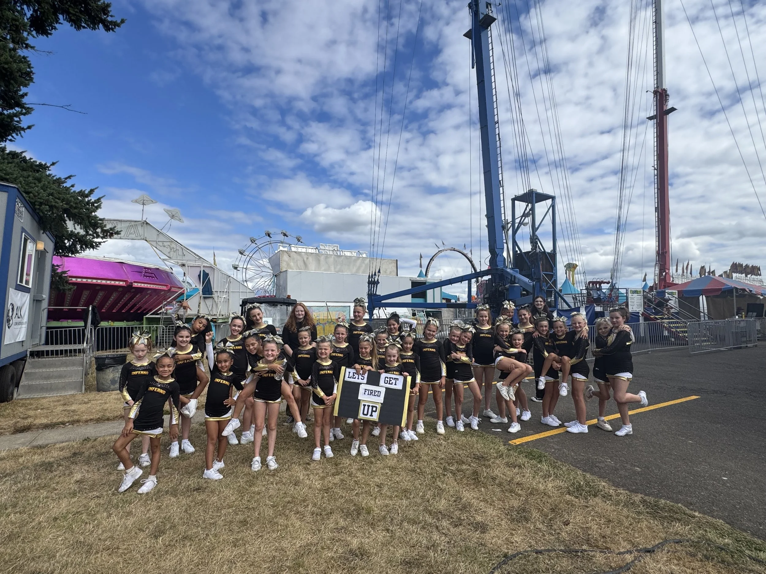 Cheerleader team posing in front of a Ferris wheel at the fairground