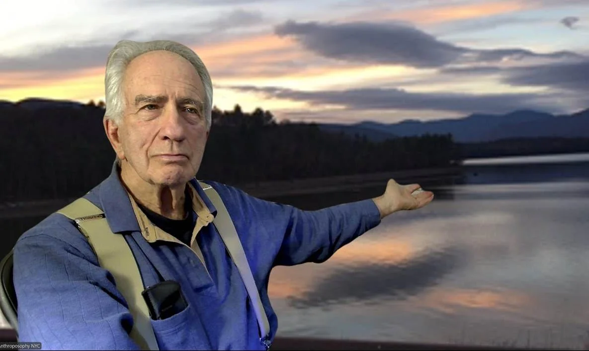 Close-up of Walter Alexander, wearing a colorful shirt, standing in front of a wooden wall.