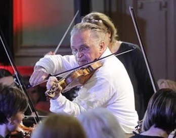 Miha playing the violin in an orchestra.