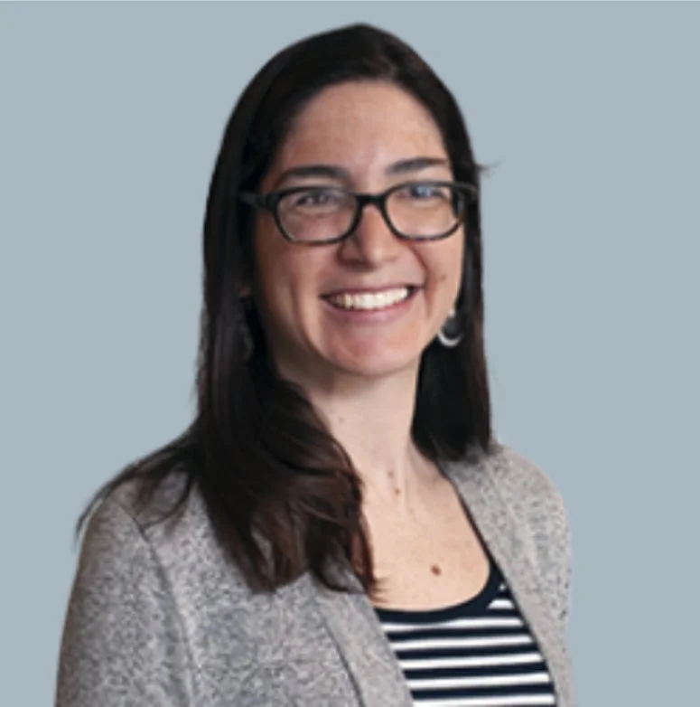 A woman with long blonde hair smiling, wearing a black and white blouse with lace details.